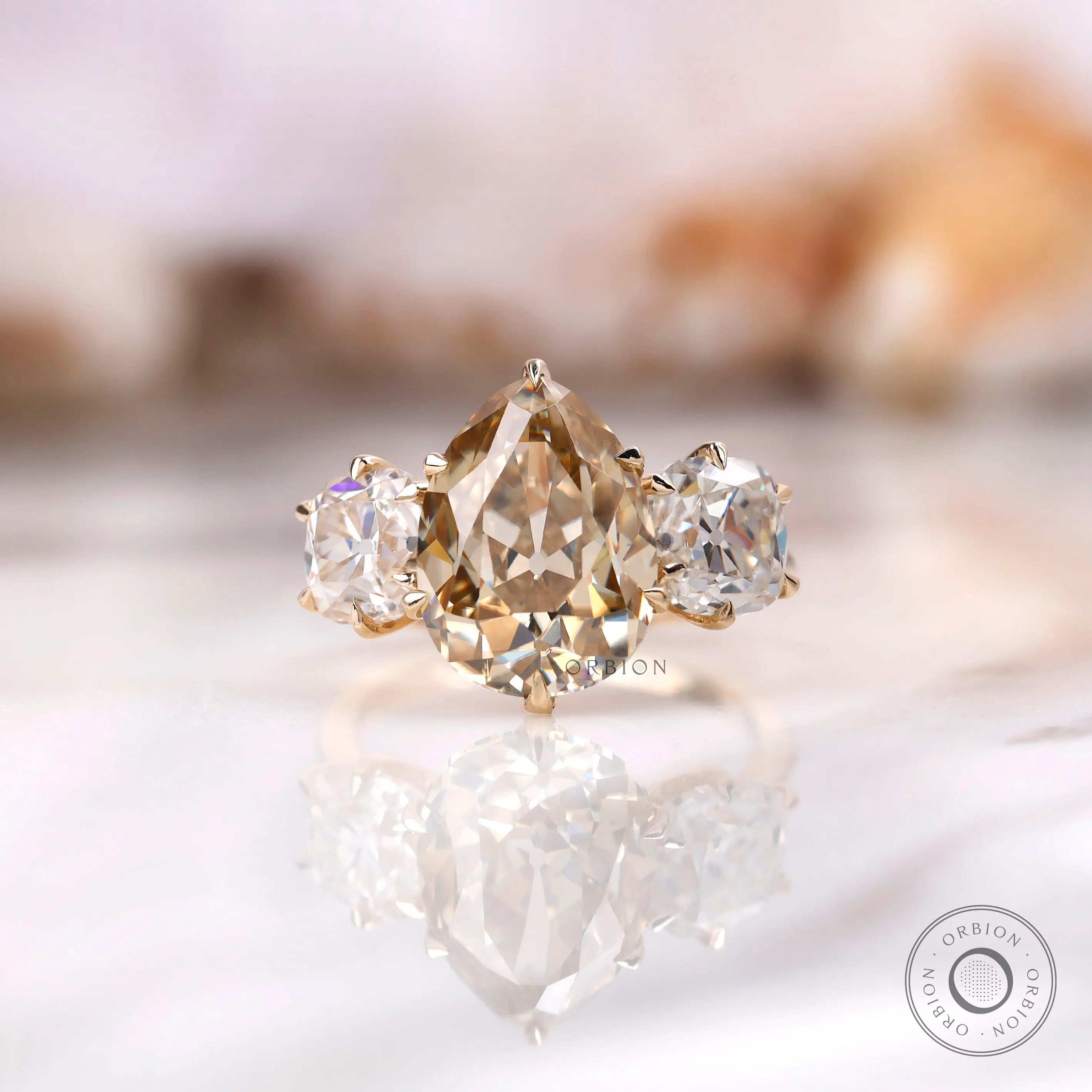 Light champagne pear old mine cut moissanite three stone ring in yellow gold