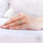 Relaxed hands resting with milgrain three stone ring