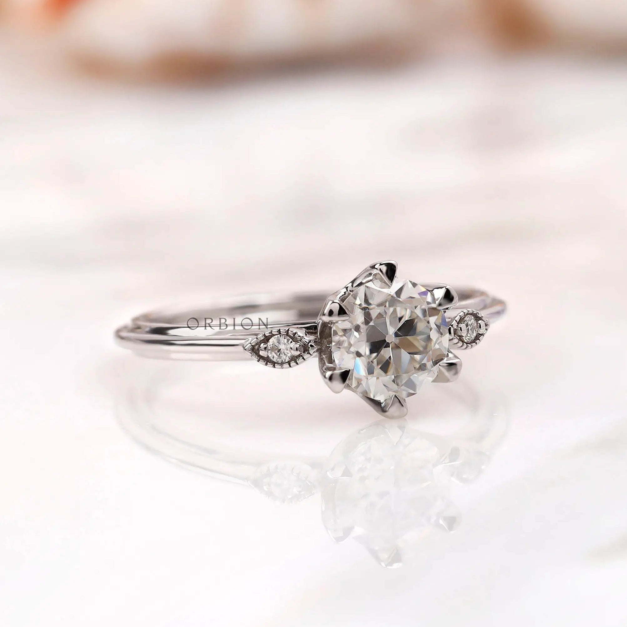 Angled close-up highlighting moissanite trio and milgrain texture