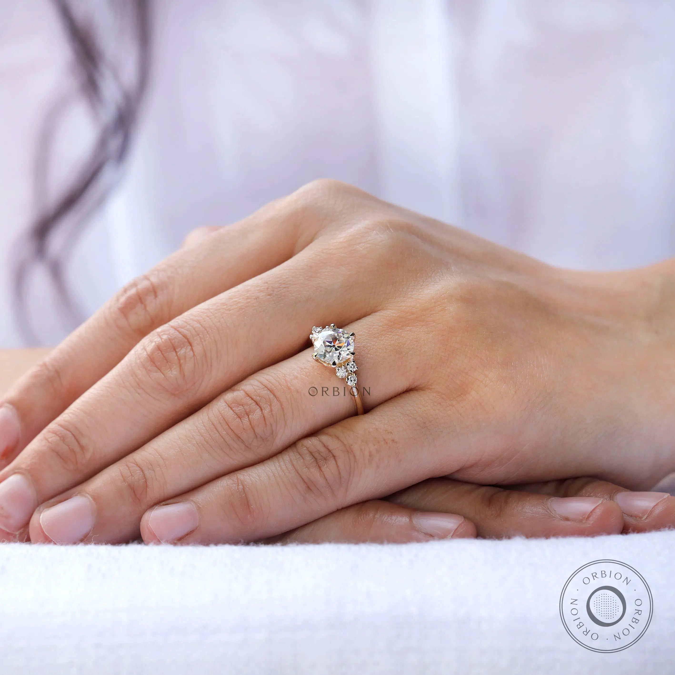 Close-up of OEC Moissanite ring worn on a finger.