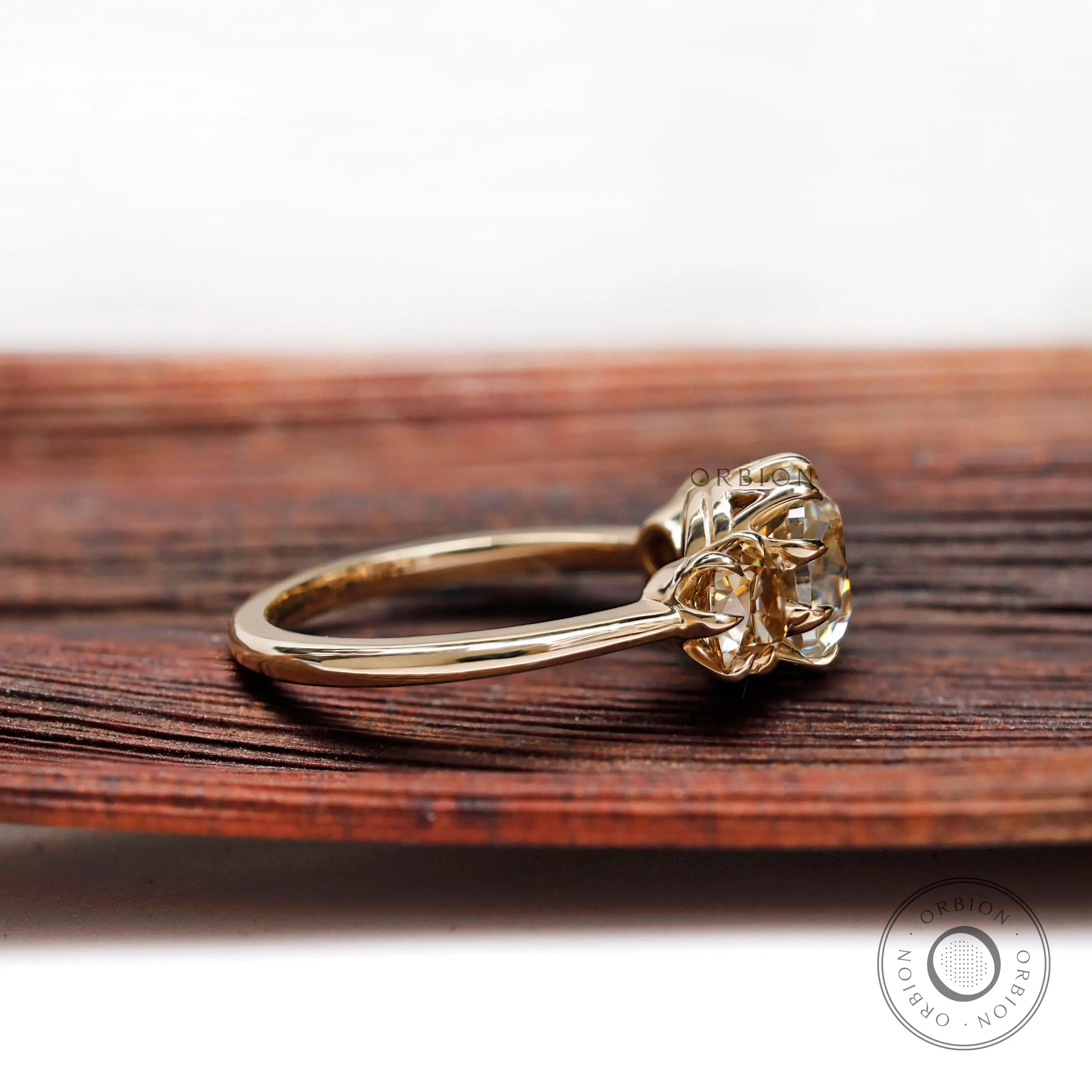 Side profile of three stone cushion moissanite ring in 10K yellow gold