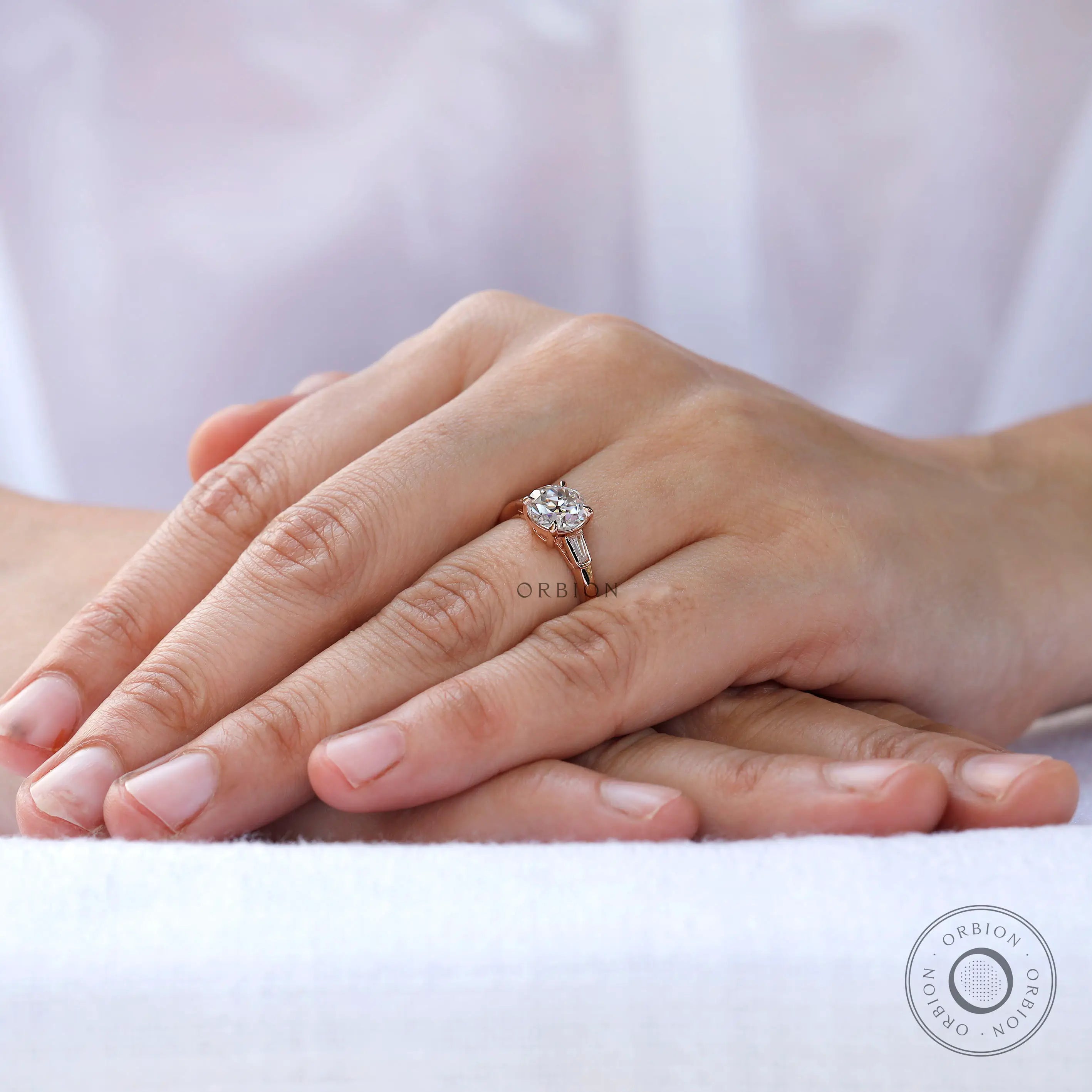 Round Old European Cut moissanite three stone ring in rose gold on hand view