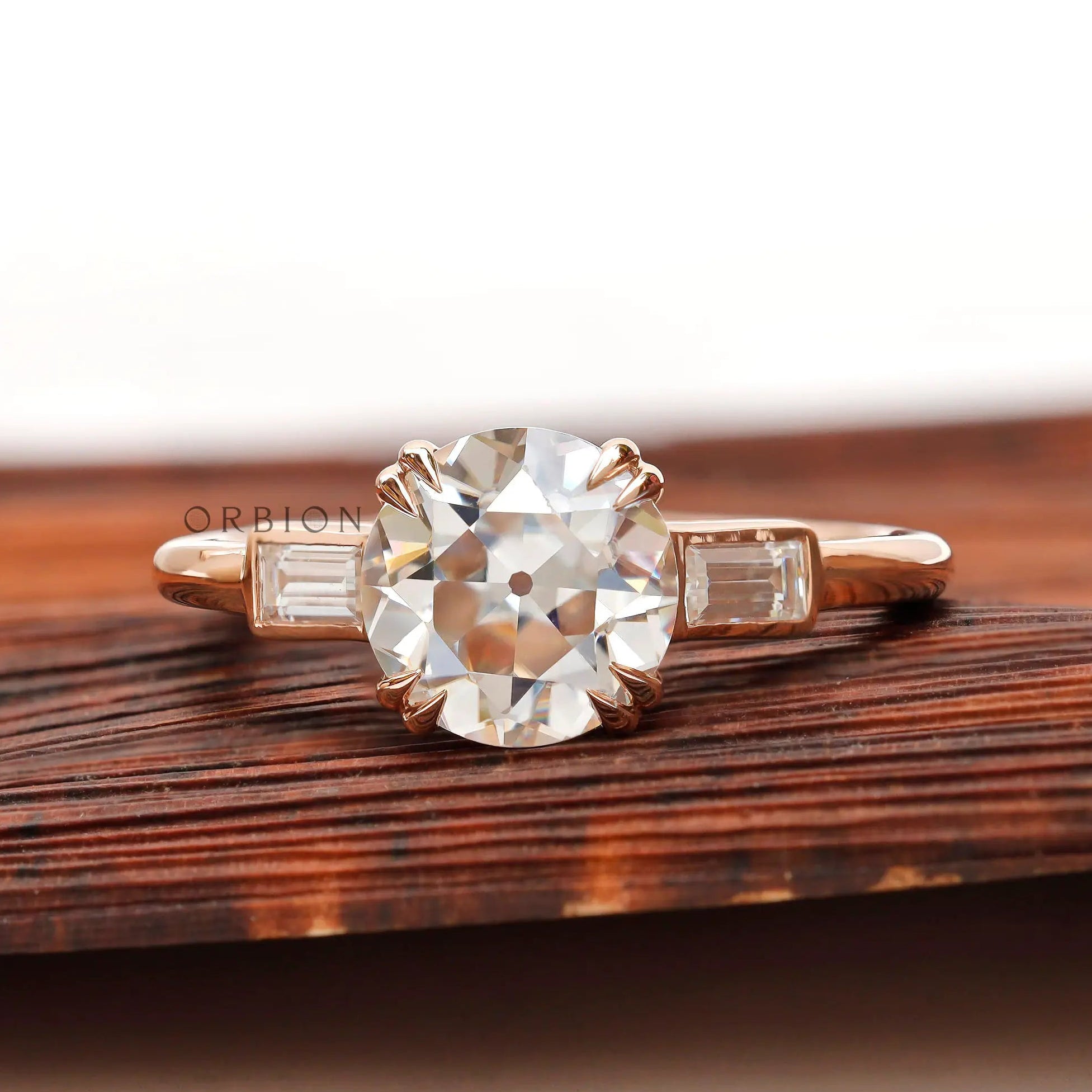 Moissanite three-stone round Old European cut ring with baguette side stones in 10K yellow gold