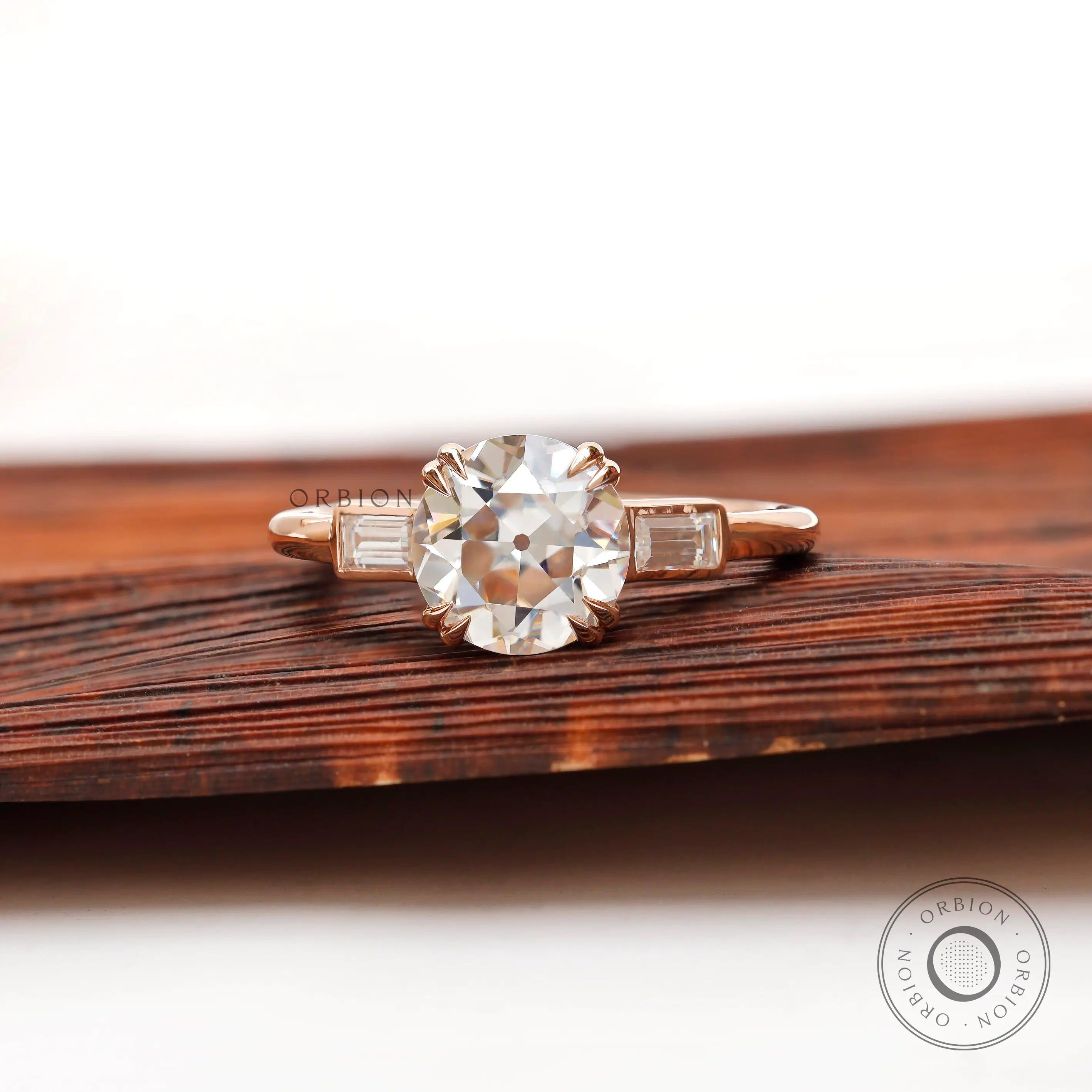 Moissanite three-stone round Old European cut ring with baguette side stones in 10K yellow gold