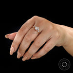 Close-up of Moissanite three-stone ring with round Old European cut center stone and baguette side stones on a finger