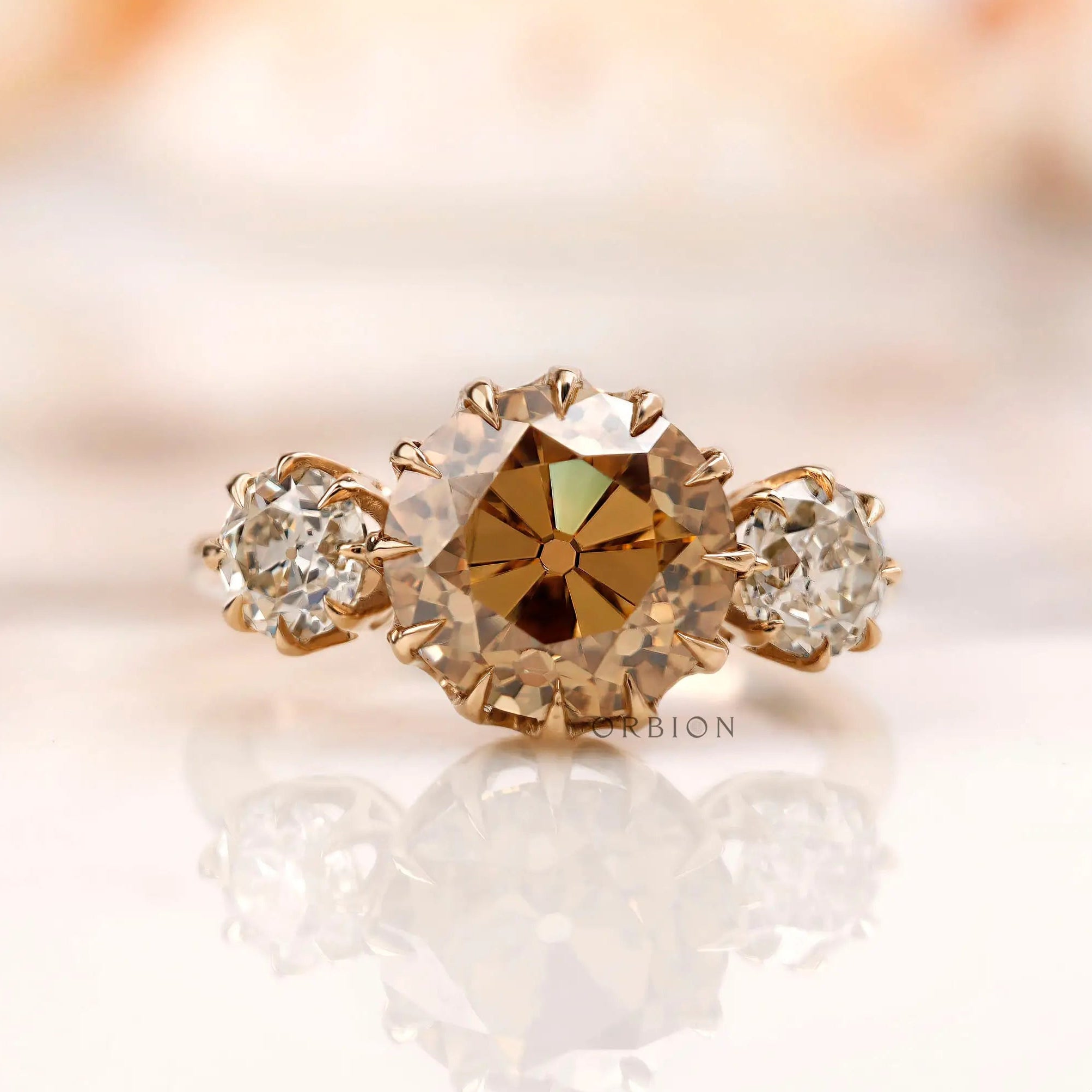 Light champagne round Old European cut moissanite three stone ring in 10K yellow gold