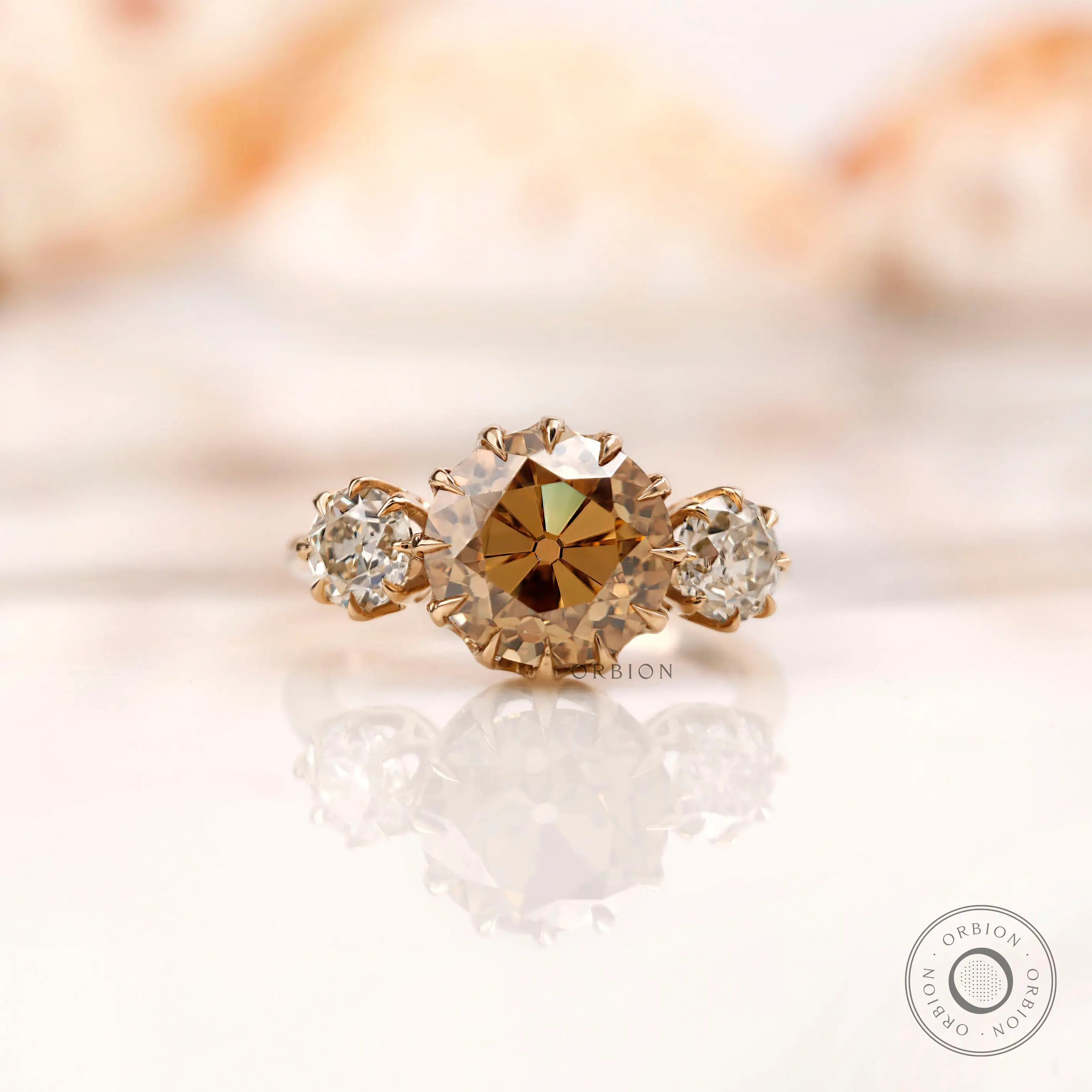 Light champagne round Old European cut moissanite three stone ring in 10K yellow gold