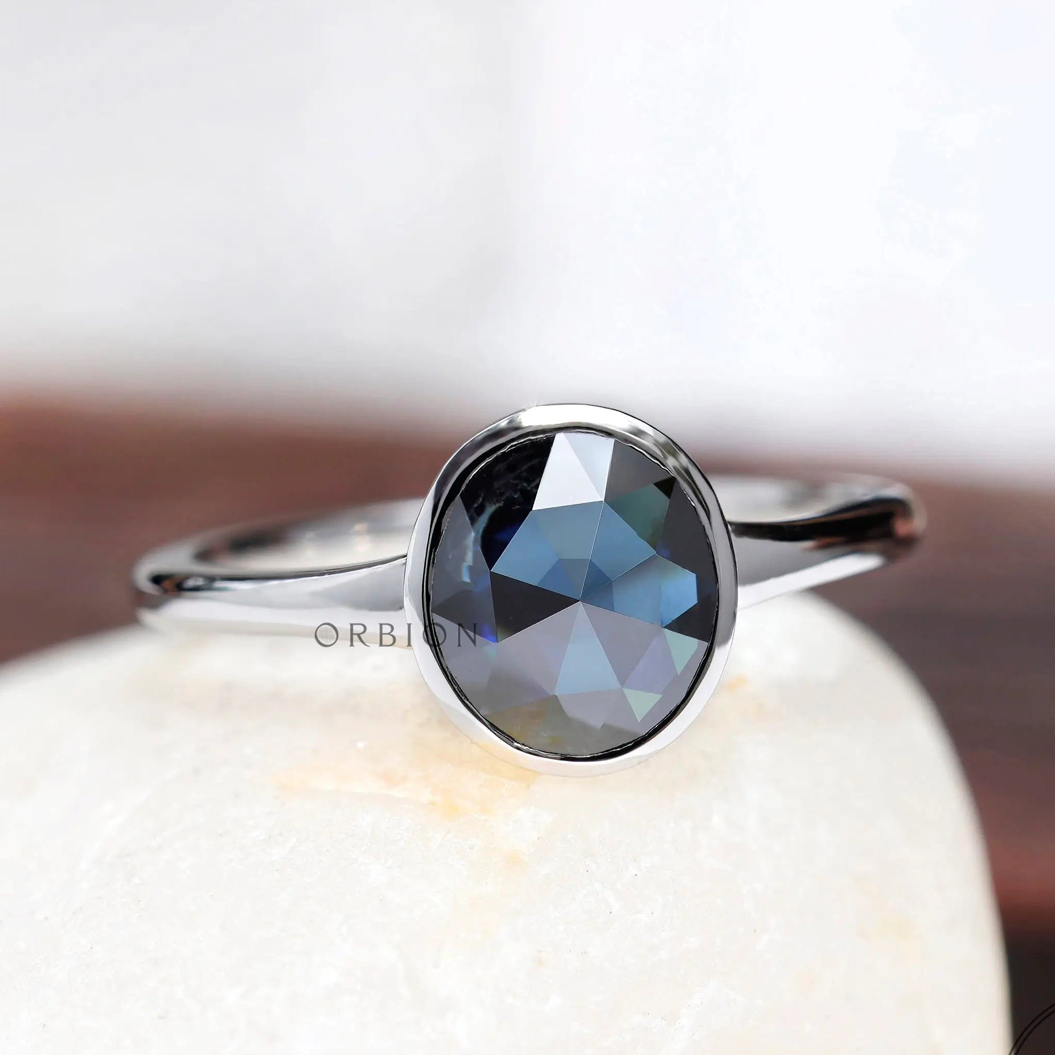 Blue rose cut oval moissanite solitaire bezel ring in 10K white gold front view