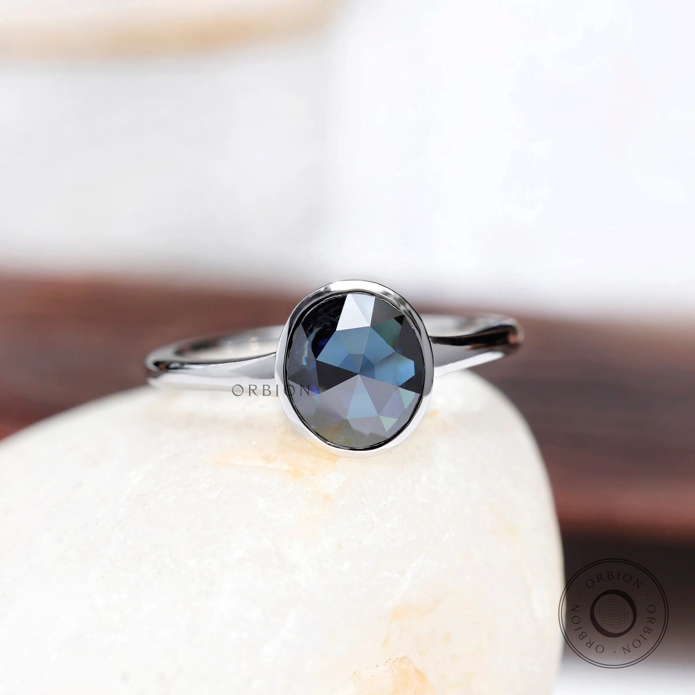 Blue rose cut oval moissanite solitaire bezel ring in 10K white gold front view