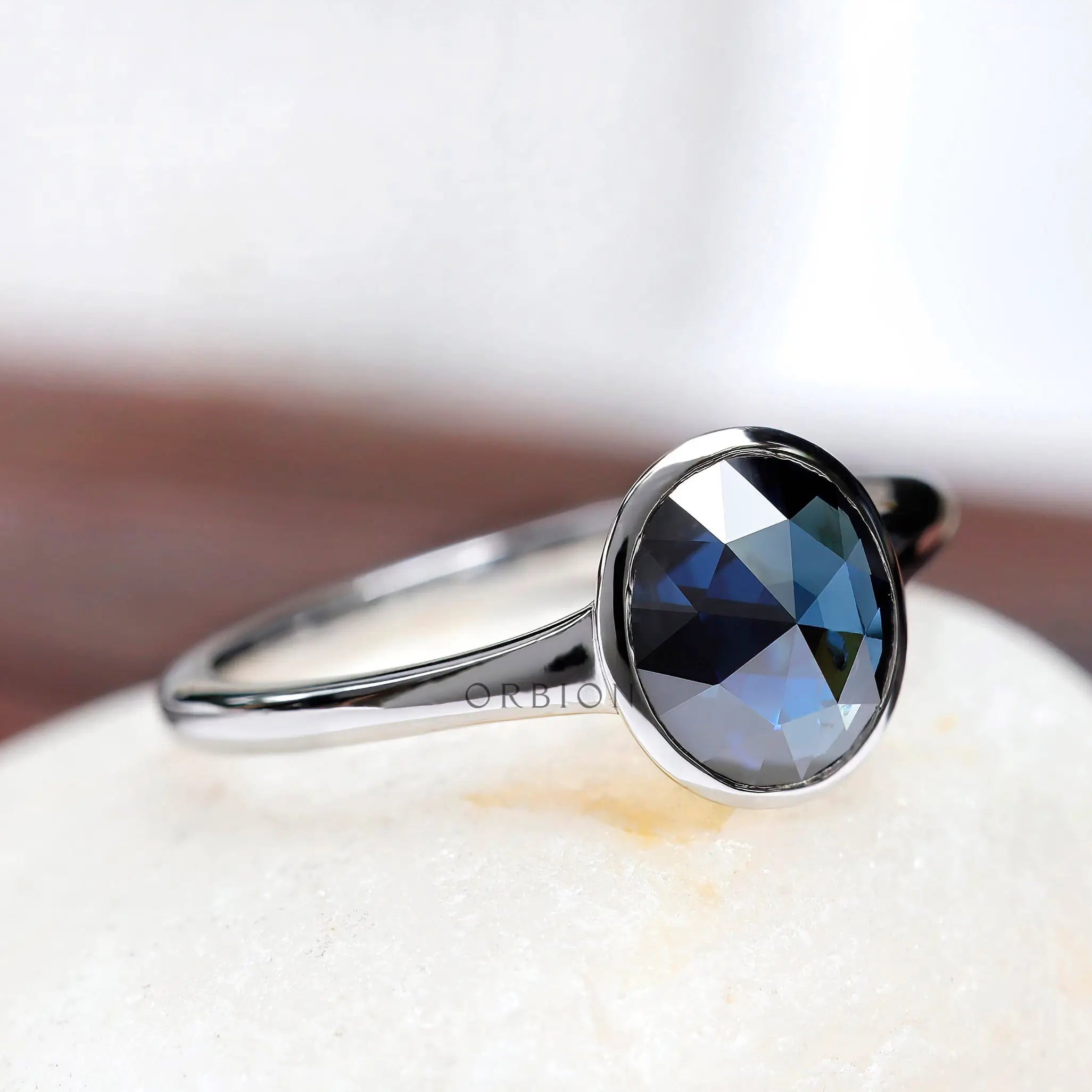 Angled view of oval blue moissanite solitaire engagement ring