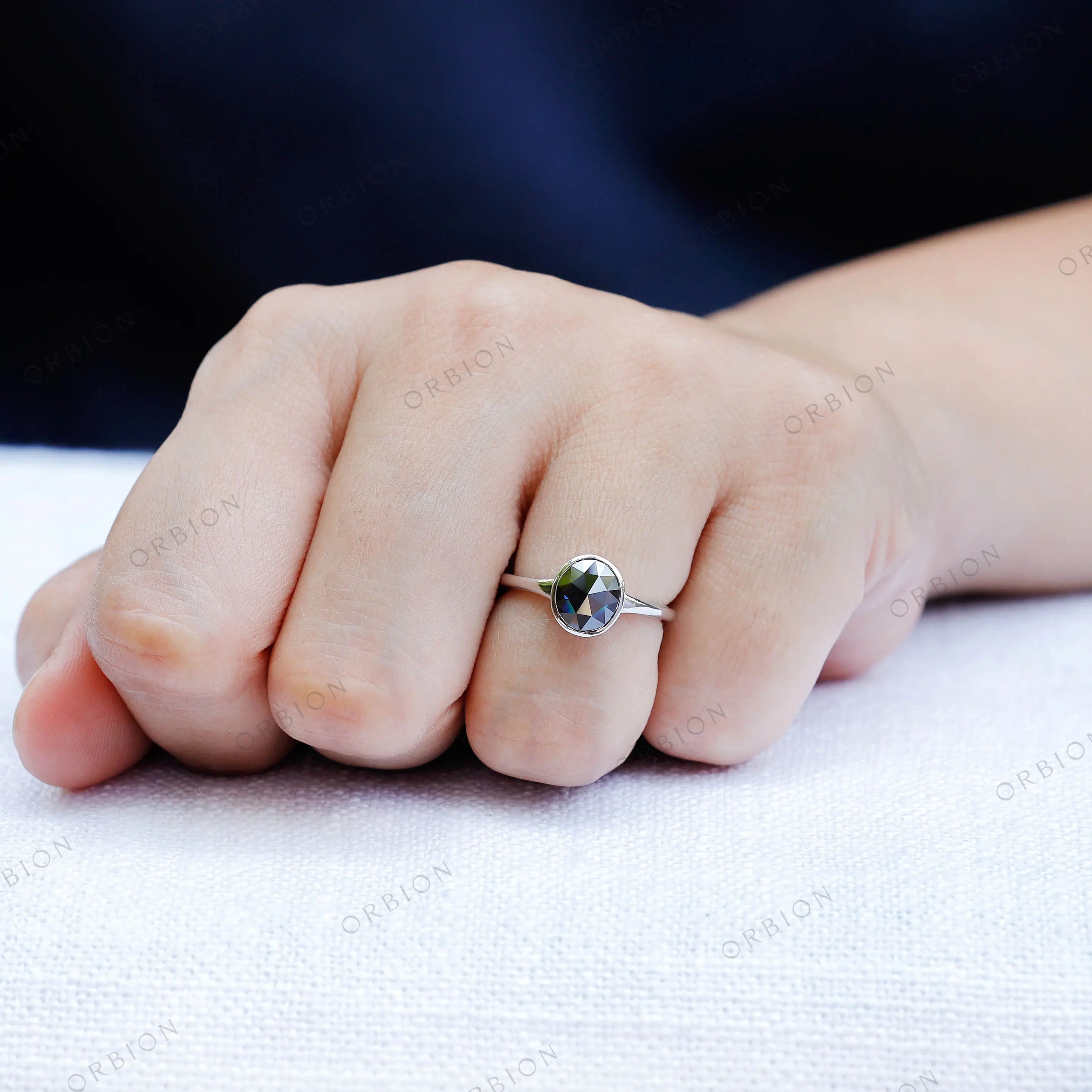 Close up of blue moissanite bezel solitaire ring on finger