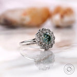 Blue green Old European cut moissanite cluster ring rotating in 10K white gold
