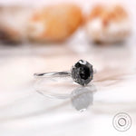 Angled view highlighting the round grey moissanite solitaire in a white gold