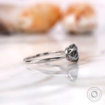 Side profile showcasing the slim band and elevated grey moissanite setting
