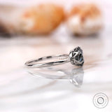 Side profile showcasing the slim band and elevated grey moissanite setting