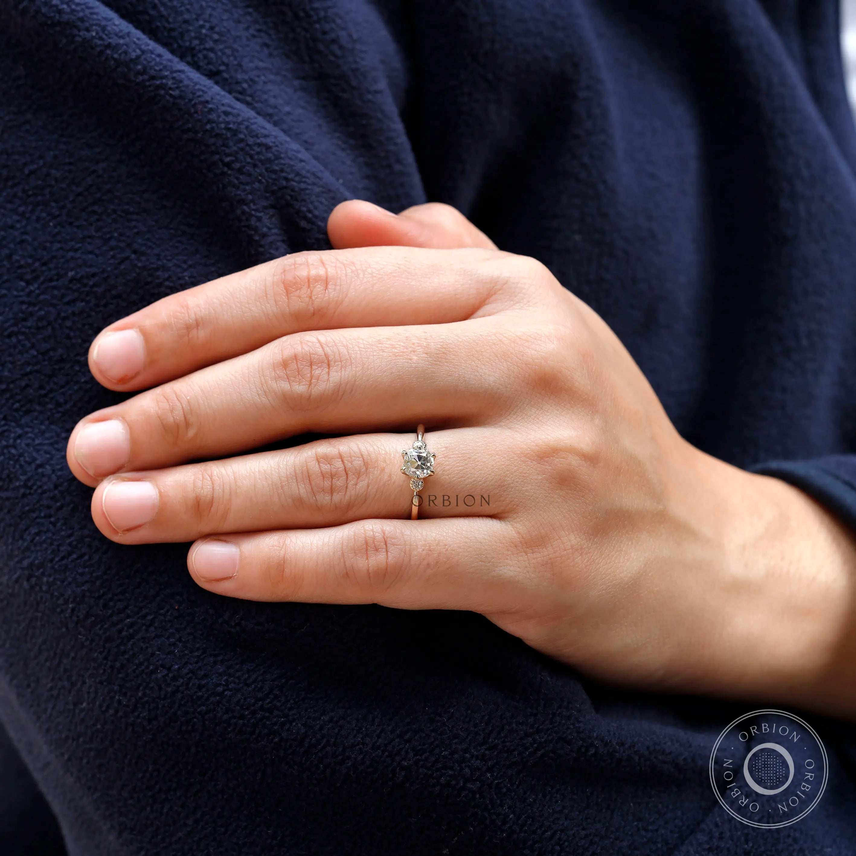 Hand model showcasing the 10K yellow gold moissanite engagement ring with a square cushion center stone.