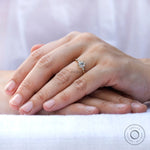 Elegant and sophisticated moissanite engagement ring in 10K yellow gold on a hand model's finger.