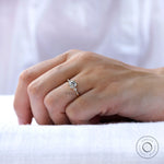 Moissanite engagement ring with a round brilliant-cut side stone, showing its high-polish finish and tapered band.
