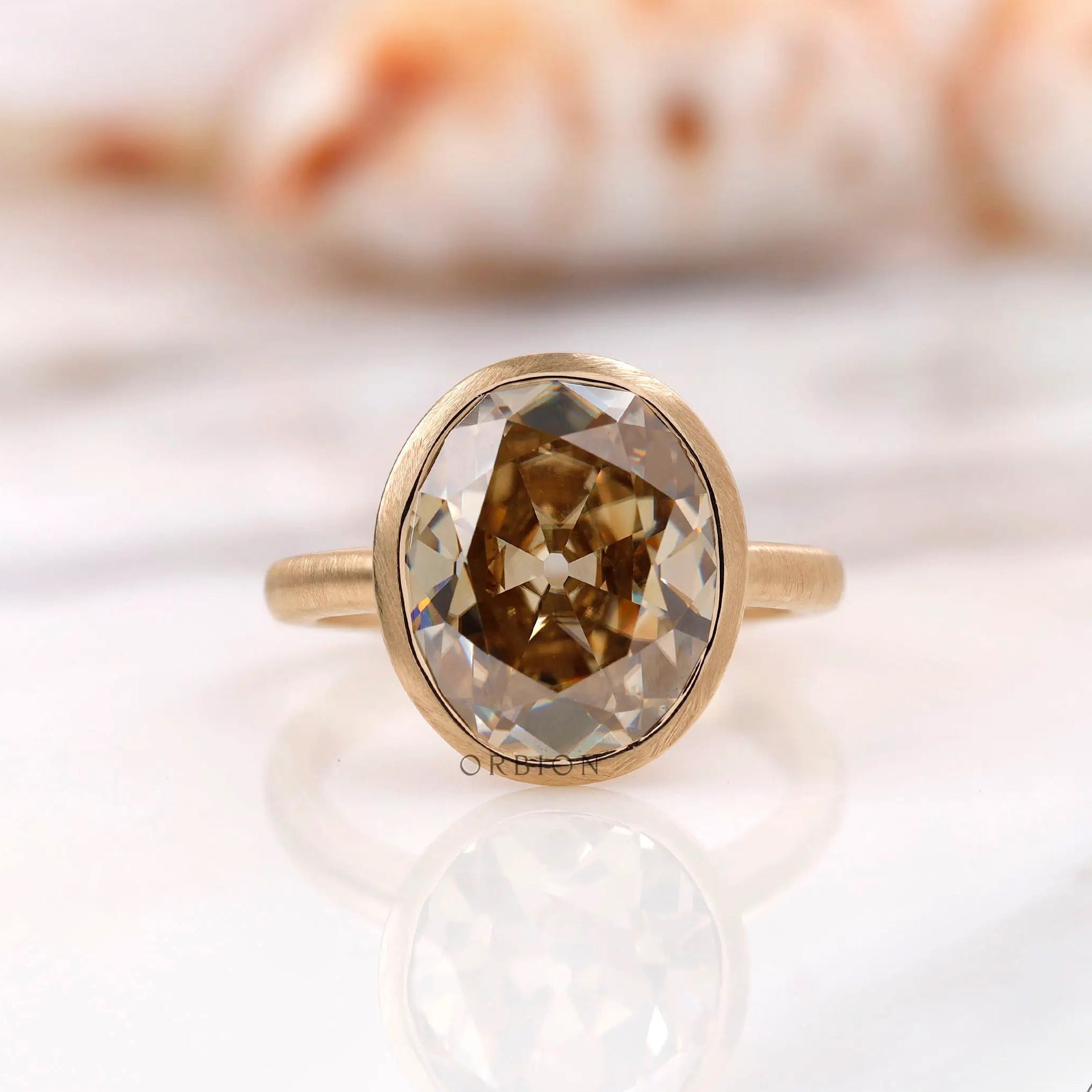 Bezel set oval champagne moissanite ring shown front view