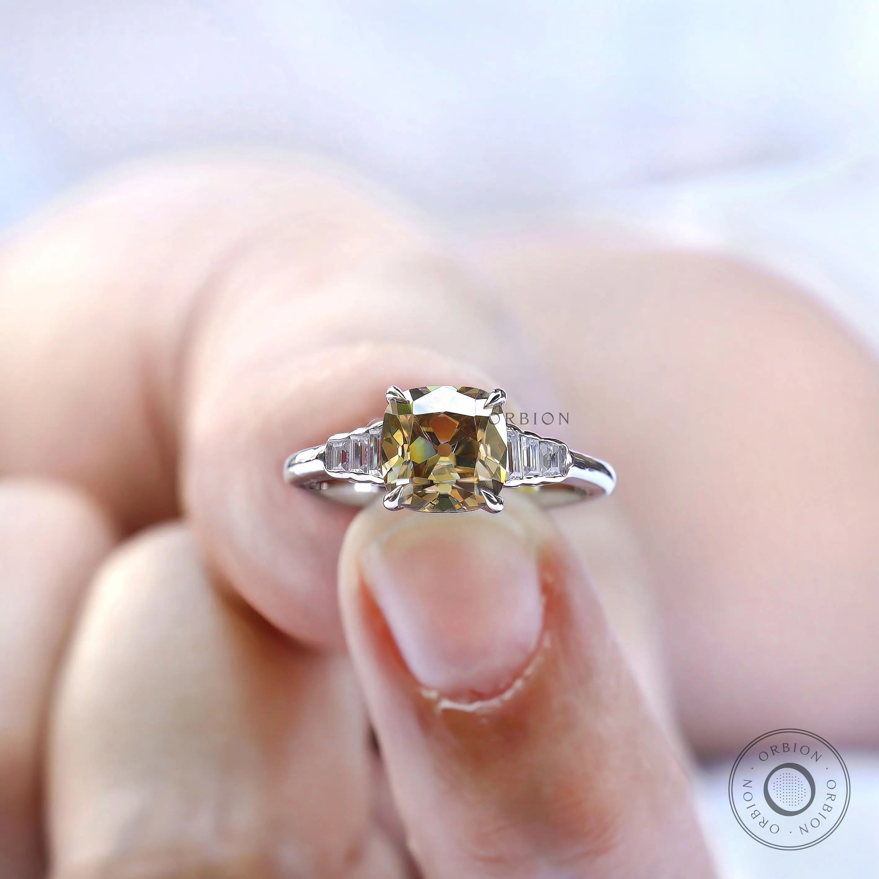 Close-up of a champagne cushion moissanite ring held on fingers