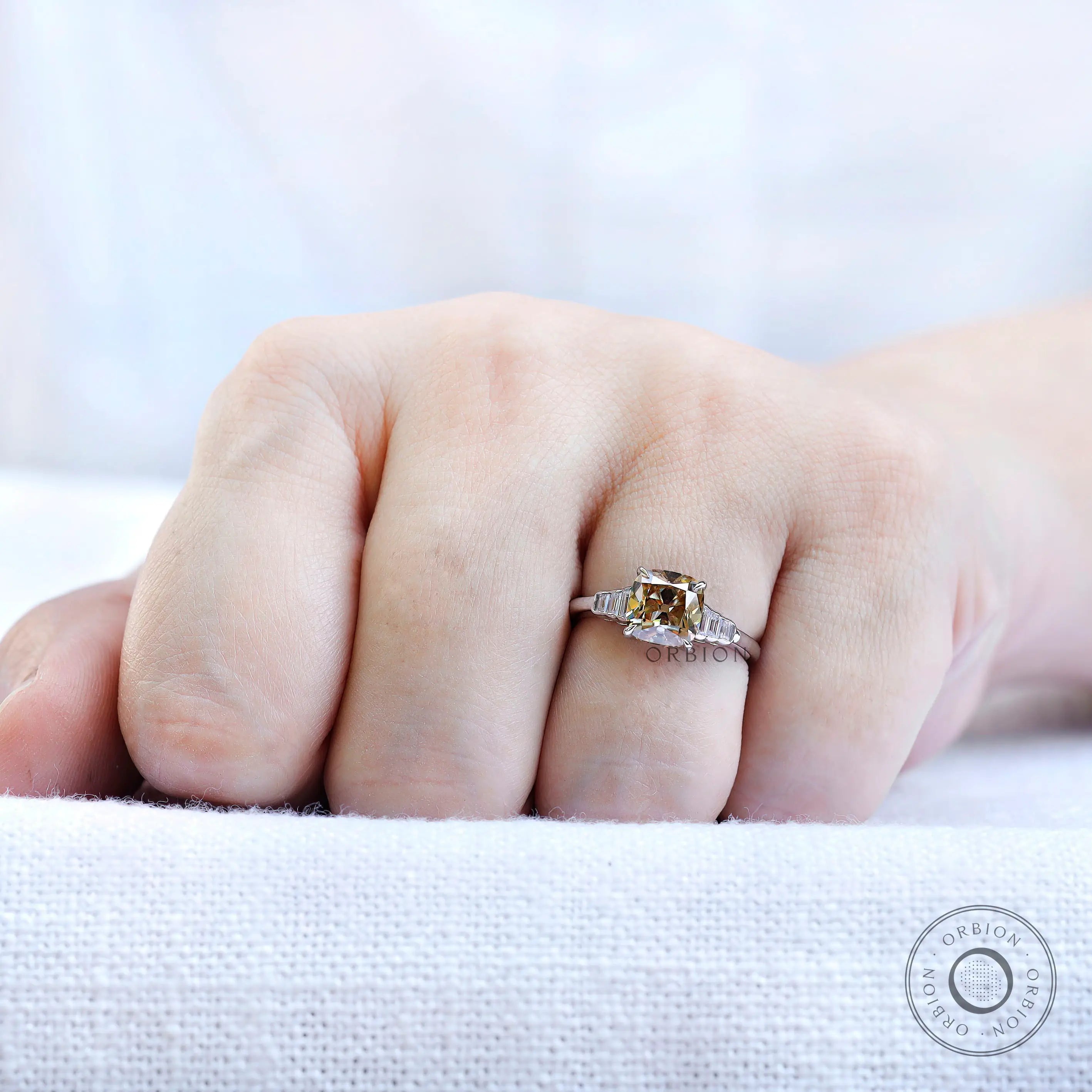 Champagne cushion moissanite ring with baguette side stones worn on hand