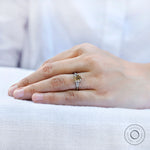 Hand wearing a champagne cushion moissanite engagement ring with baguette side stones