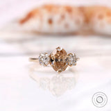 Oval champagne moissanite three stone ring shown angled
