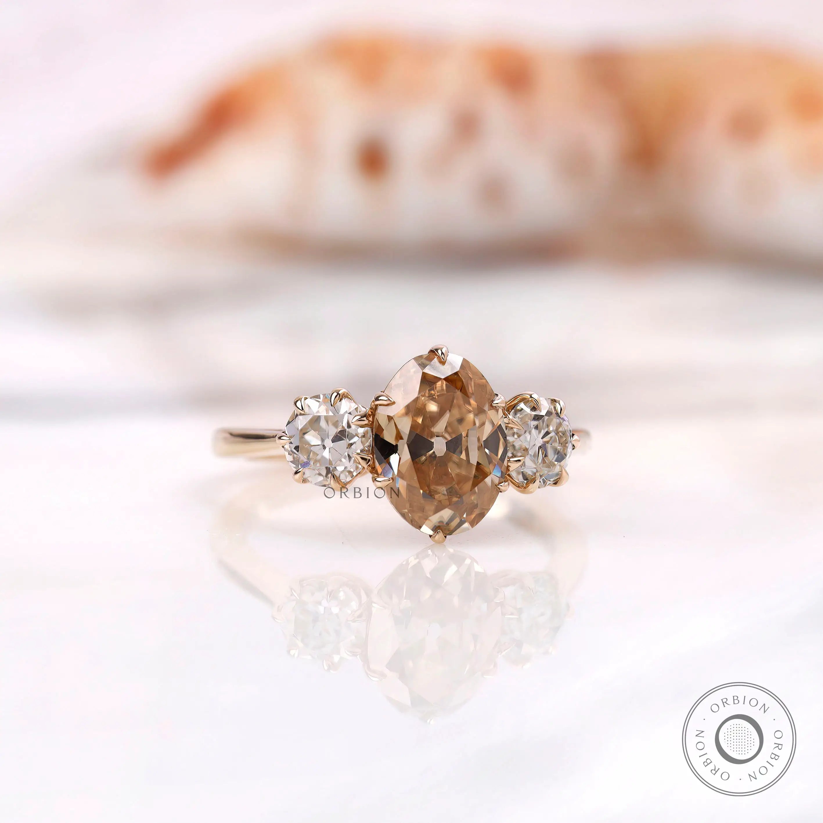 Oval champagne moissanite three stone ring shown angled