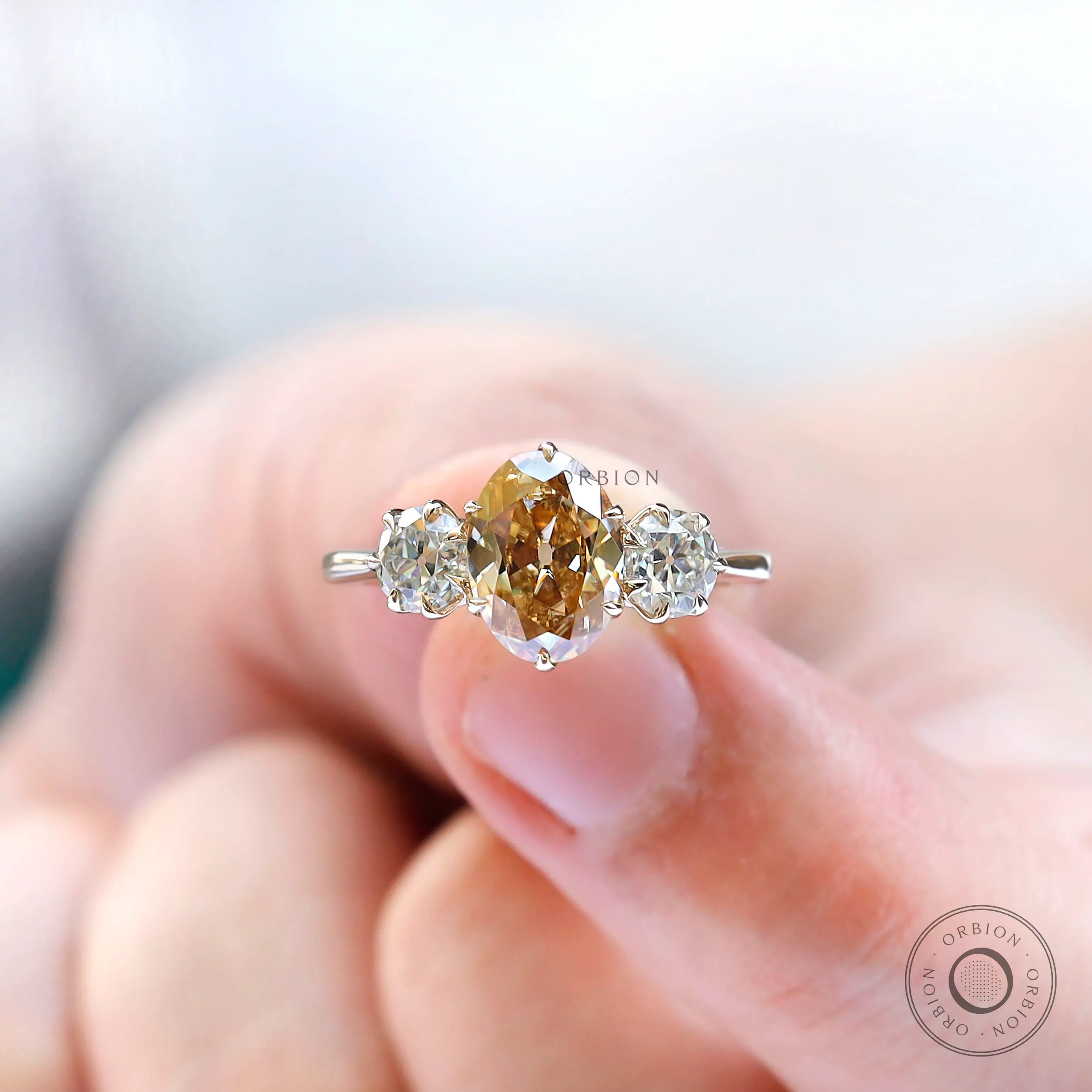 Oval champagne moissanite three stone ring worn on hand