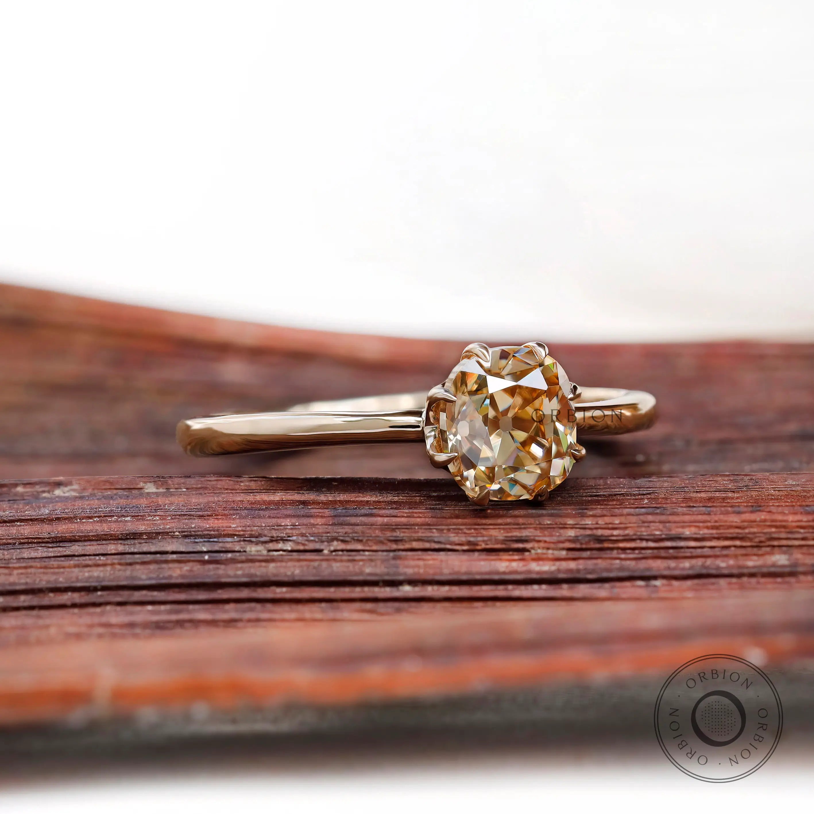 Champagne Moissanite solitaire ring with simple band, angled view on wood