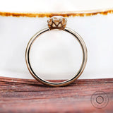 Close-up of Champagne Moissanite solitaire ring from the side on wooden surface