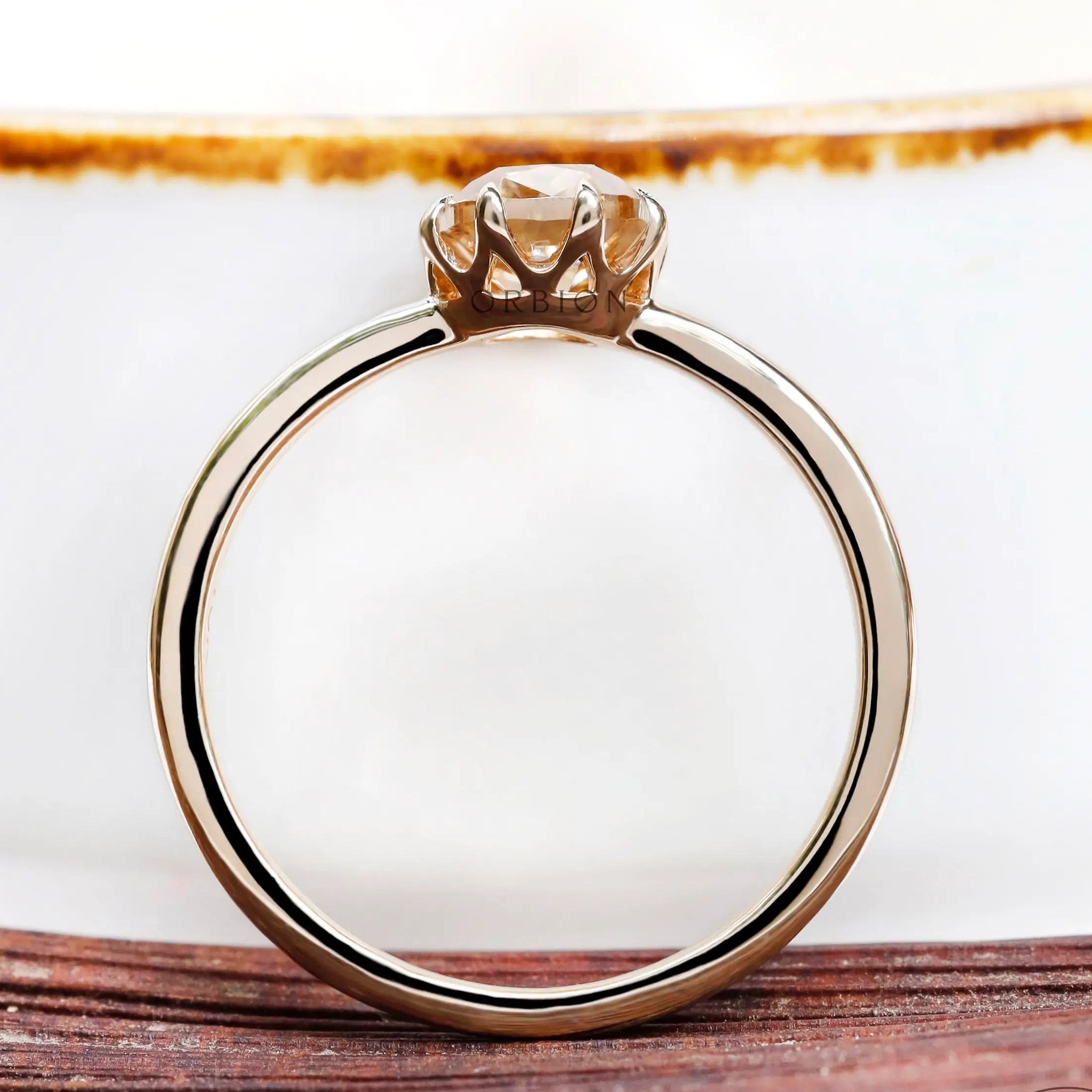 Close-up of Champagne Moissanite solitaire ring from the side on wooden surface