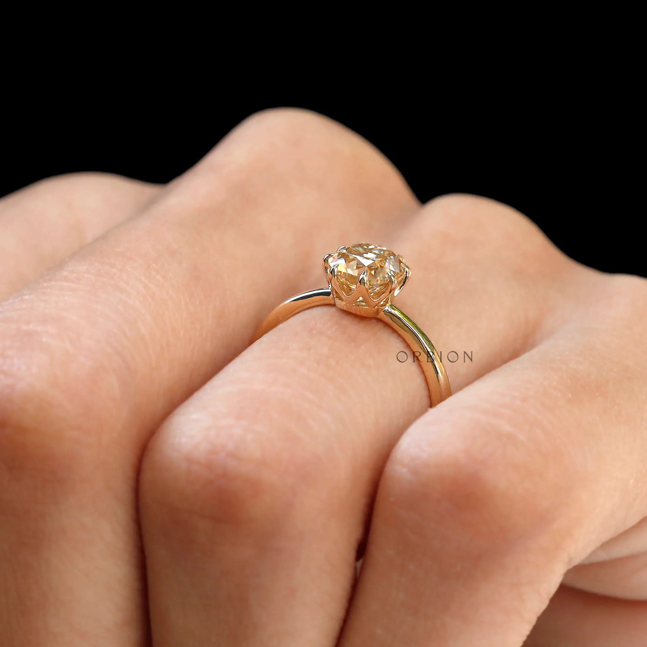 Hand wearing Champagne Moissanite solitaire engagement ring with neutral