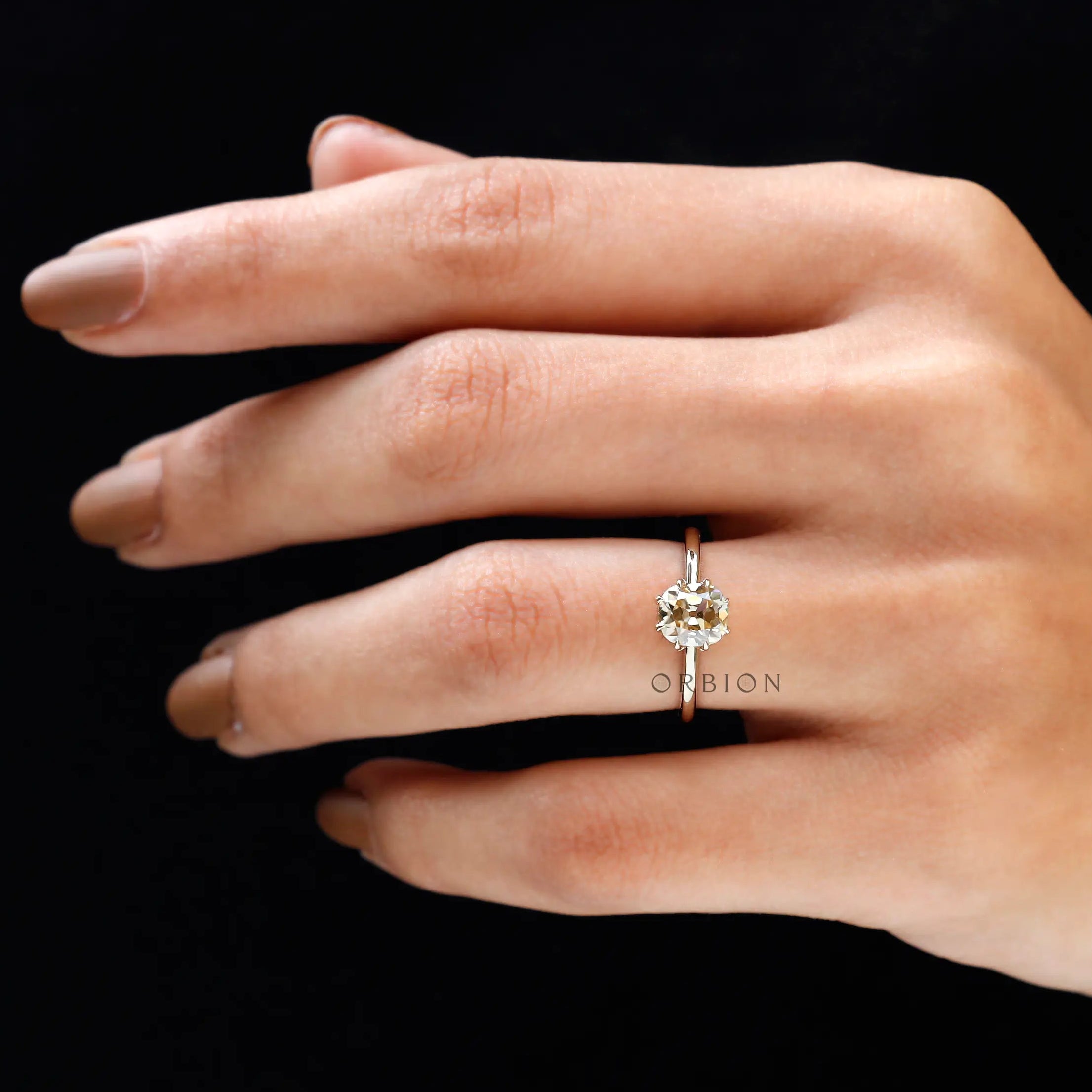 Champagne Moissanite solitaire ring on hand against dark background, elegant fit