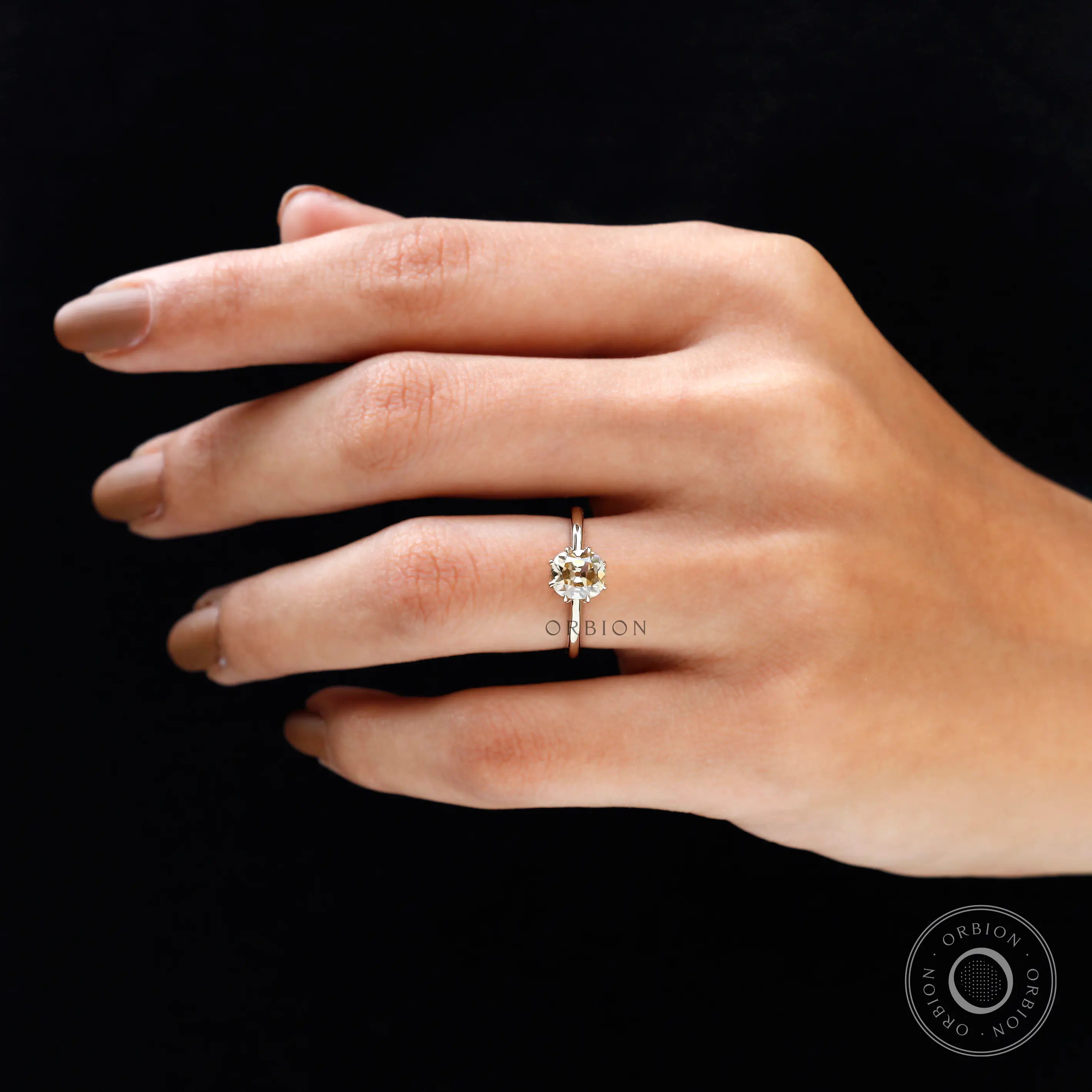 Champagne Moissanite solitaire ring on hand against dark background, elegant fit