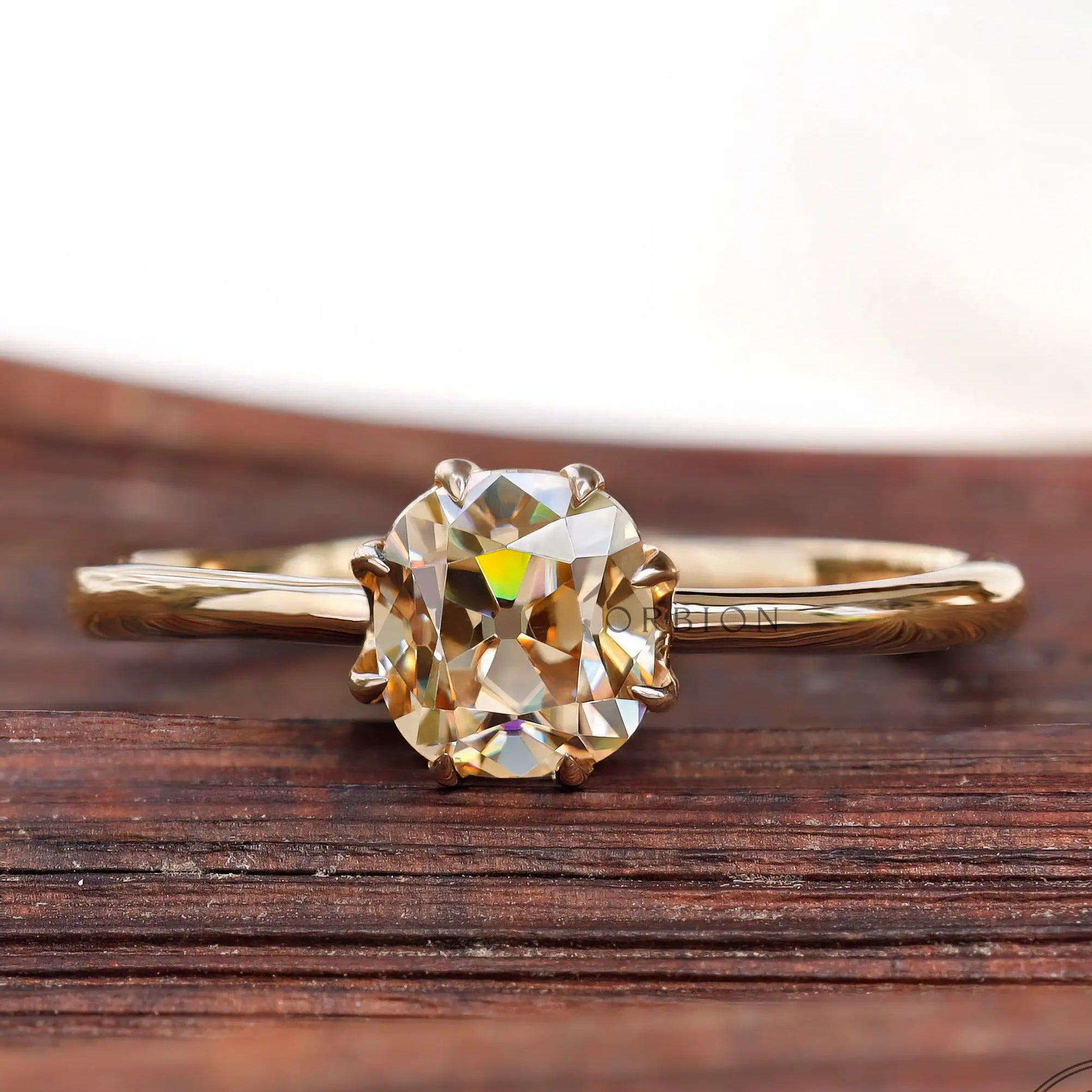 Champagne Moissanite solitaire ring in 10K Yellow Gold on wood background