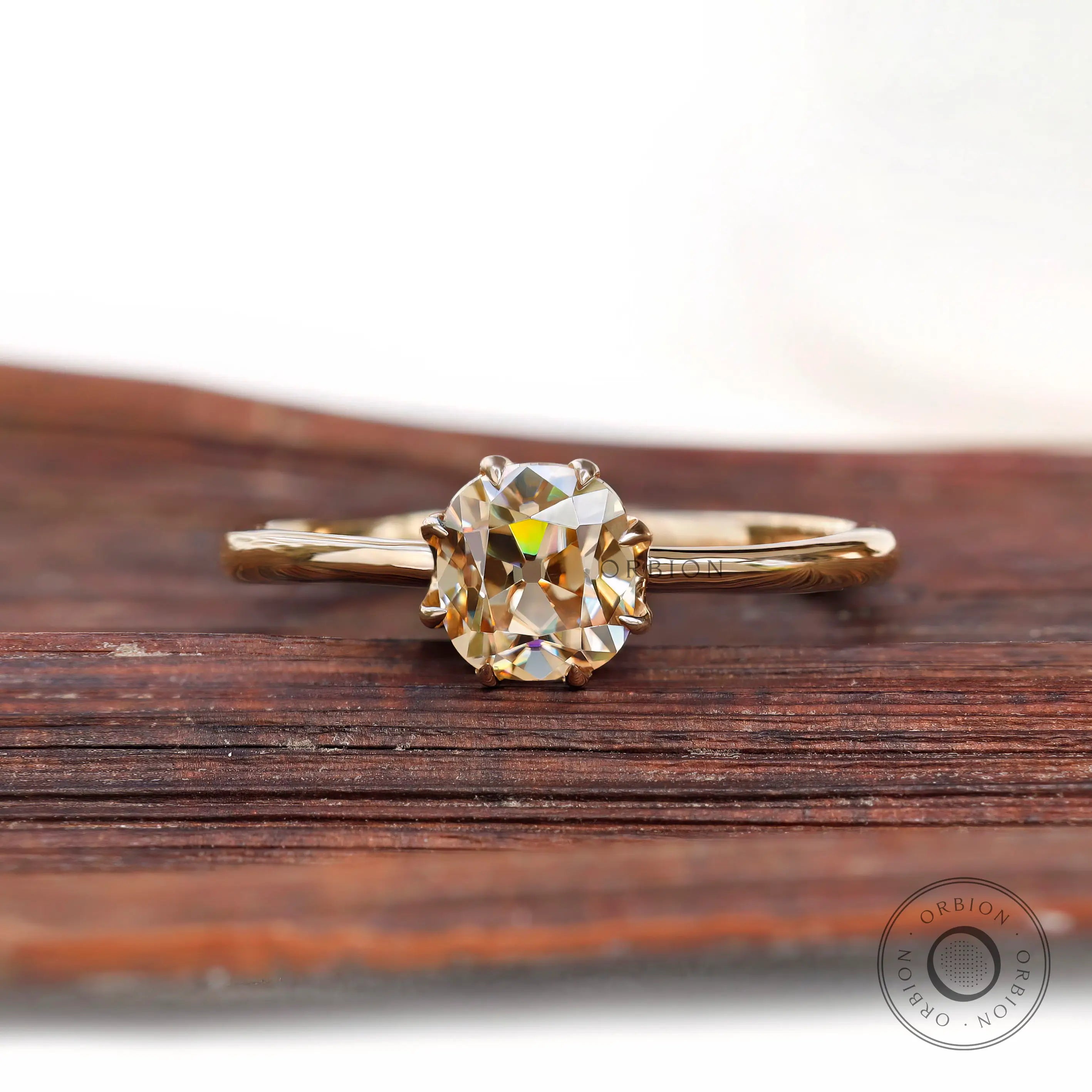 Champagne Moissanite solitaire ring in 10K Yellow Gold on wood background