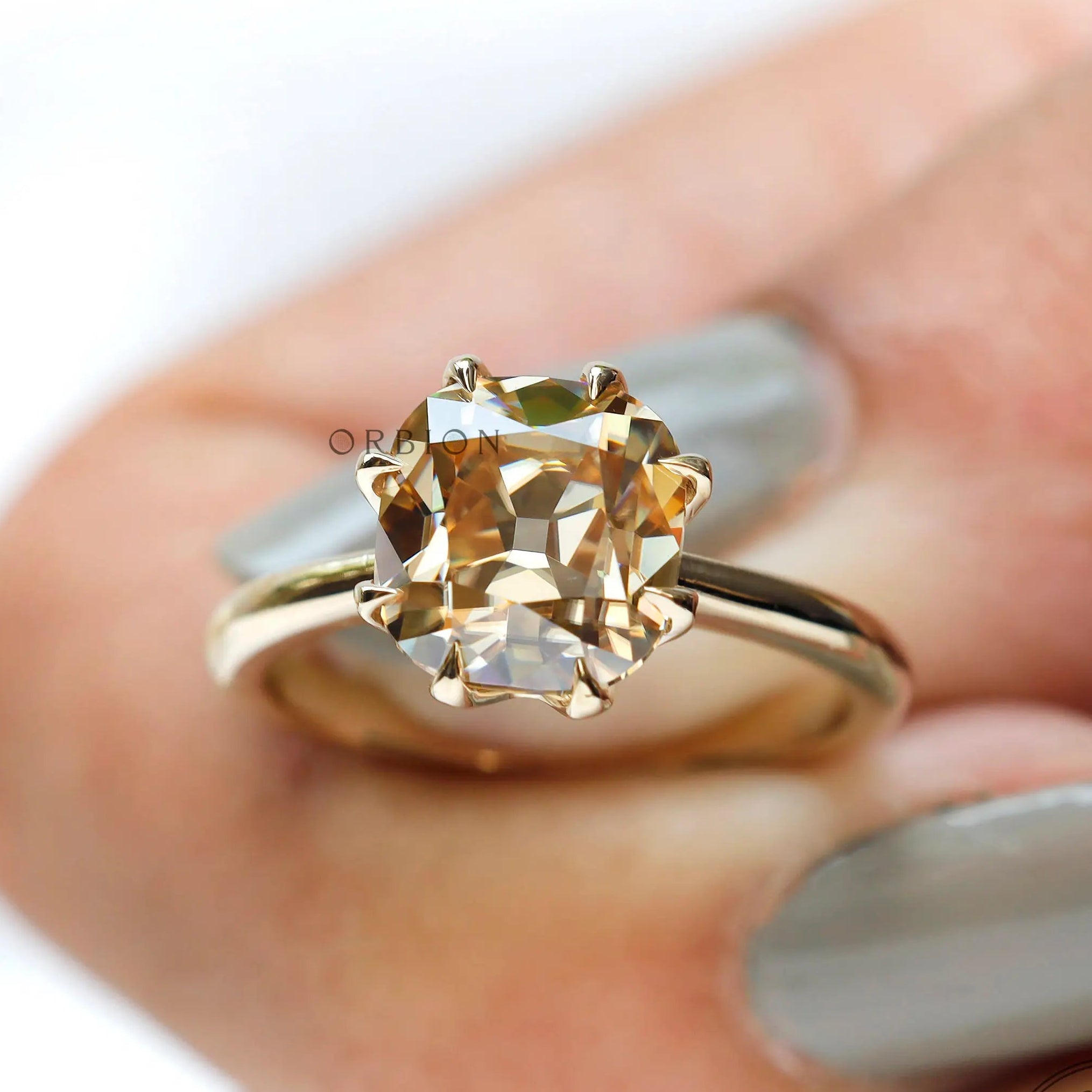 On-hand view of light champagne moissanite solitaire ring in yellow gold