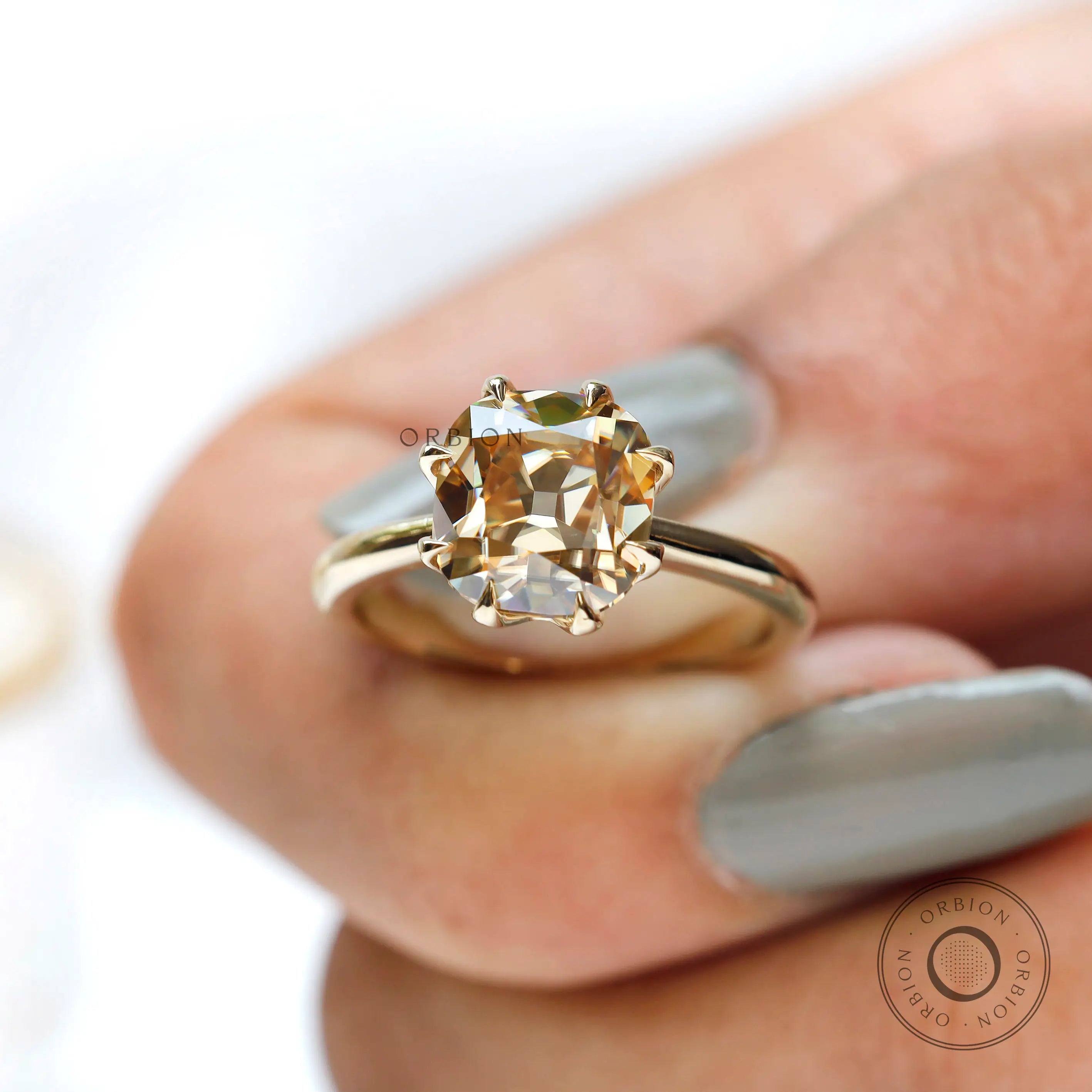 On-hand view of light champagne moissanite solitaire ring in yellow gold