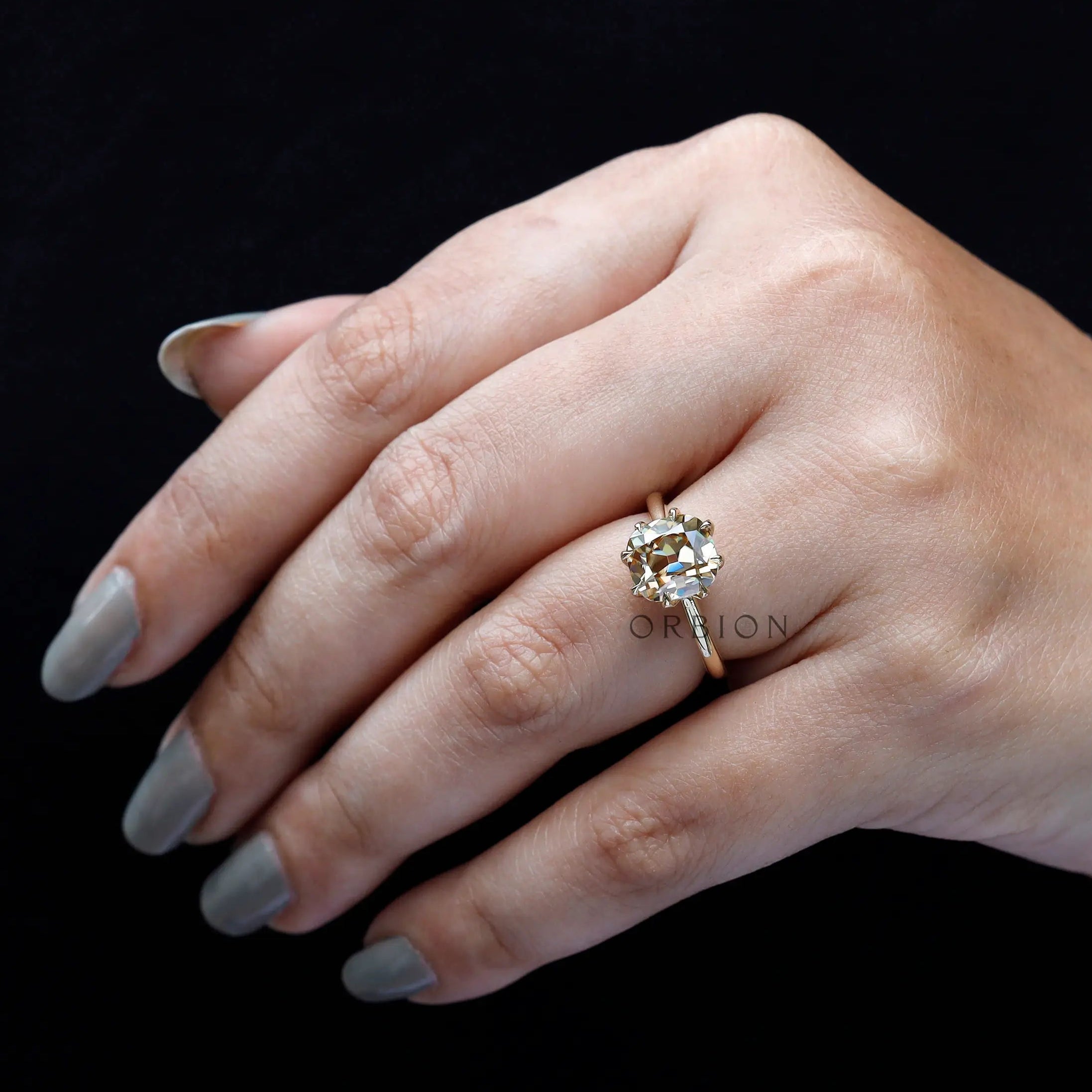 Cushion Old Mine Cut light champagne moissanite ring worn on finger close-up