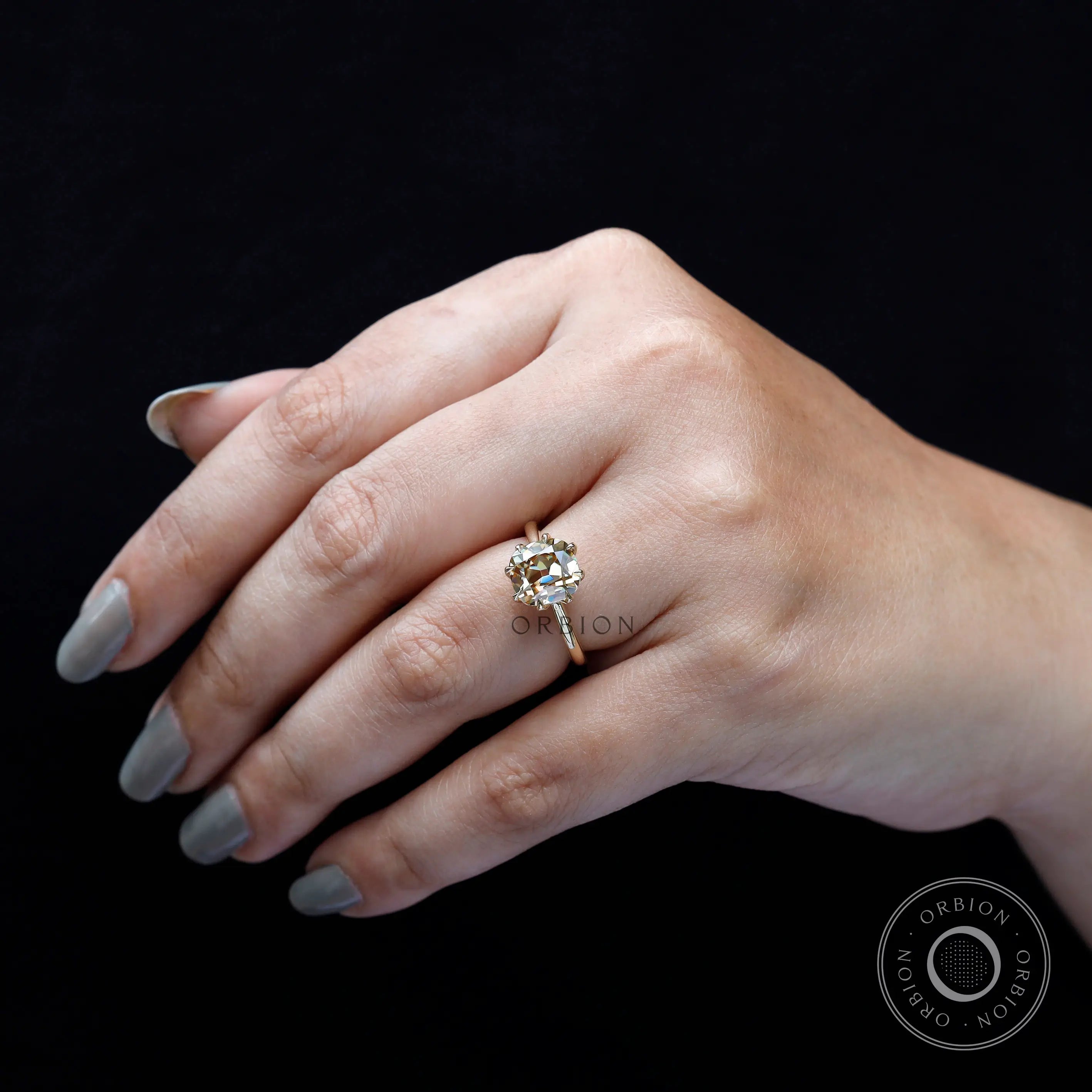 Cushion Old Mine Cut light champagne moissanite ring worn on finger close-up