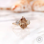 Dark champagne pear moissanite ring with round side stones
