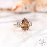 Dark champagne pear moissanite ring with round side stones
