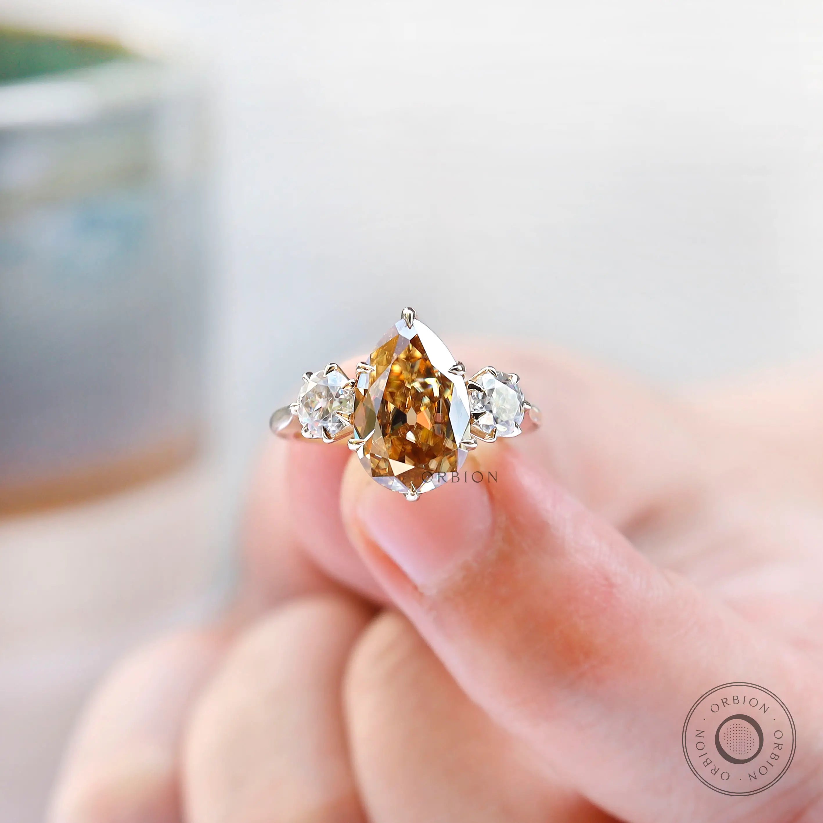 Yellow gold pear champagne moissanite  trilogy wedding ring close up