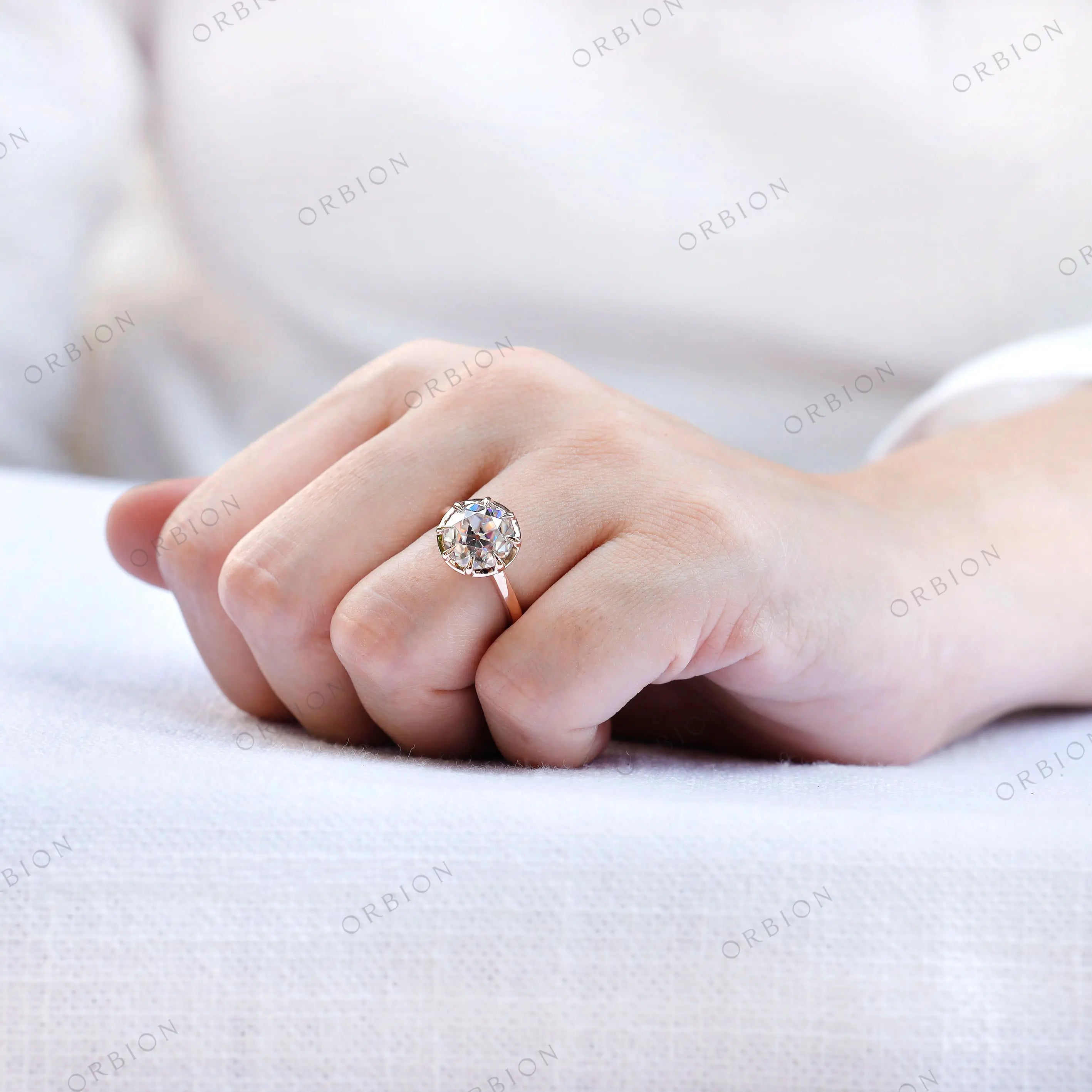 Hand-worn view of round moissanite solitaire ring in rose gold