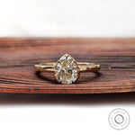 Pear moissanite solitaire ring shown front on wood
