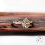 Pear moissanite solitaire ring shown angled on wood