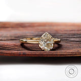 Pear moissanite solitaire ring shown angled on wood