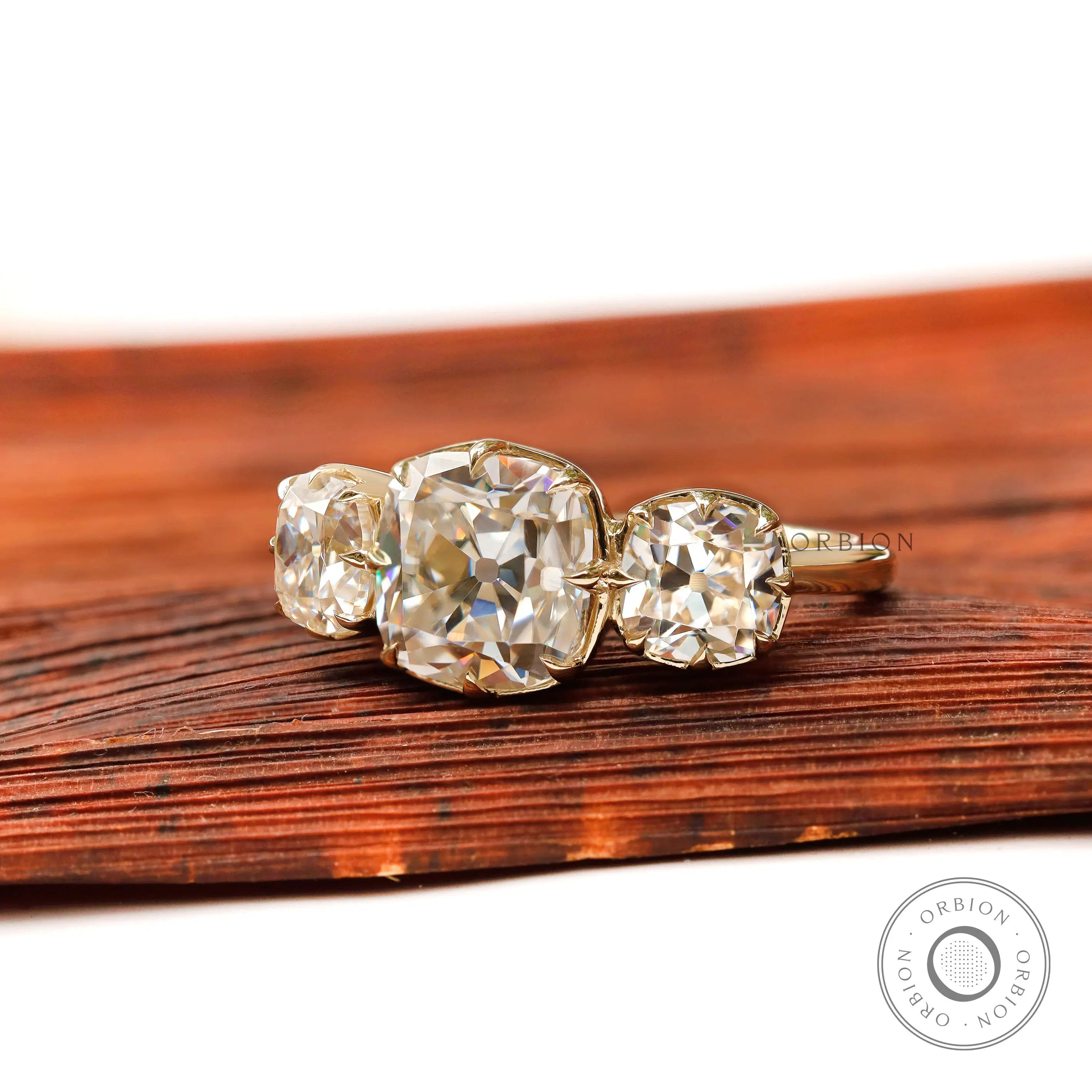 Angled view of three stone cushion moissanite ring in yellow gold