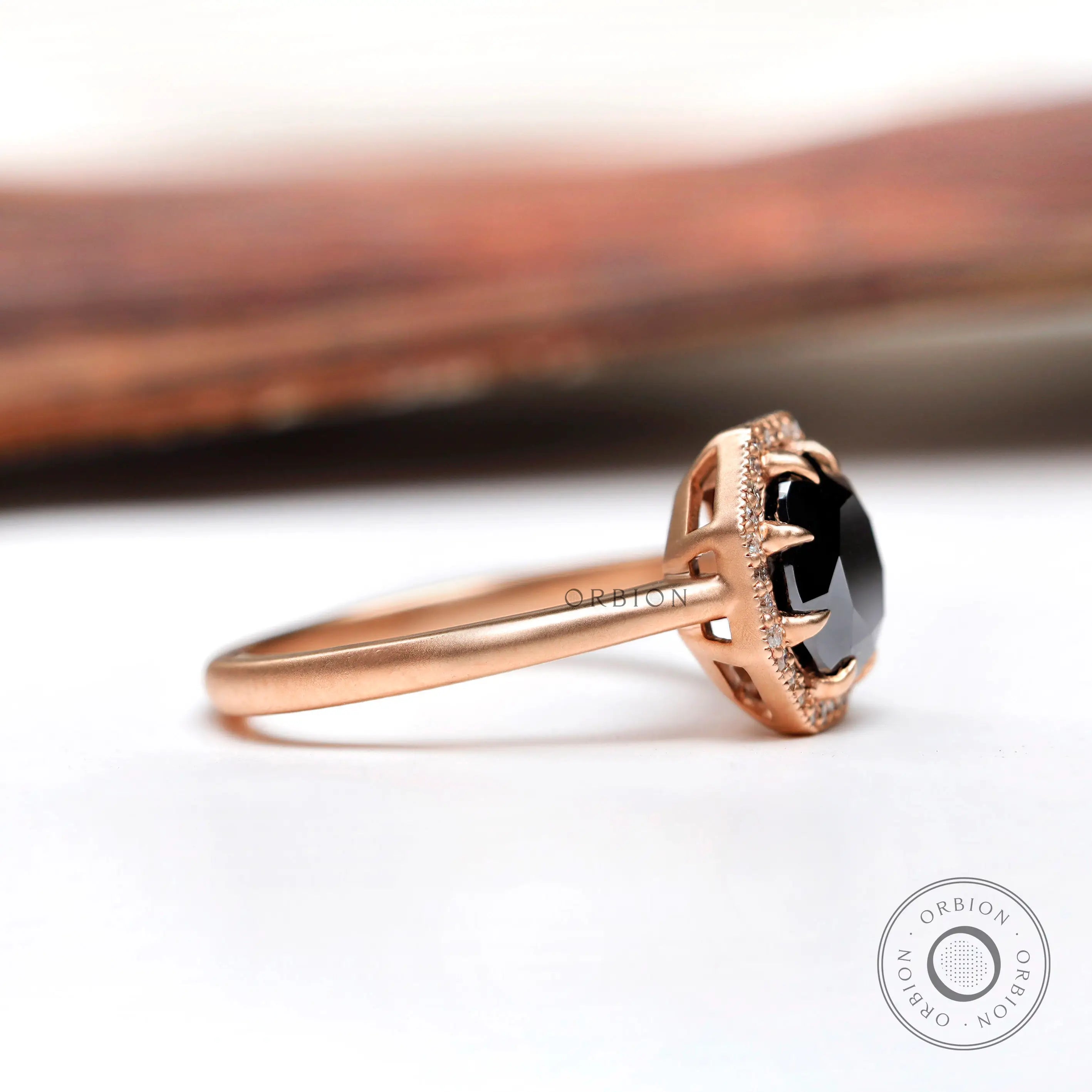 Side profile of black moissanite halo ring in 10K rose gold
